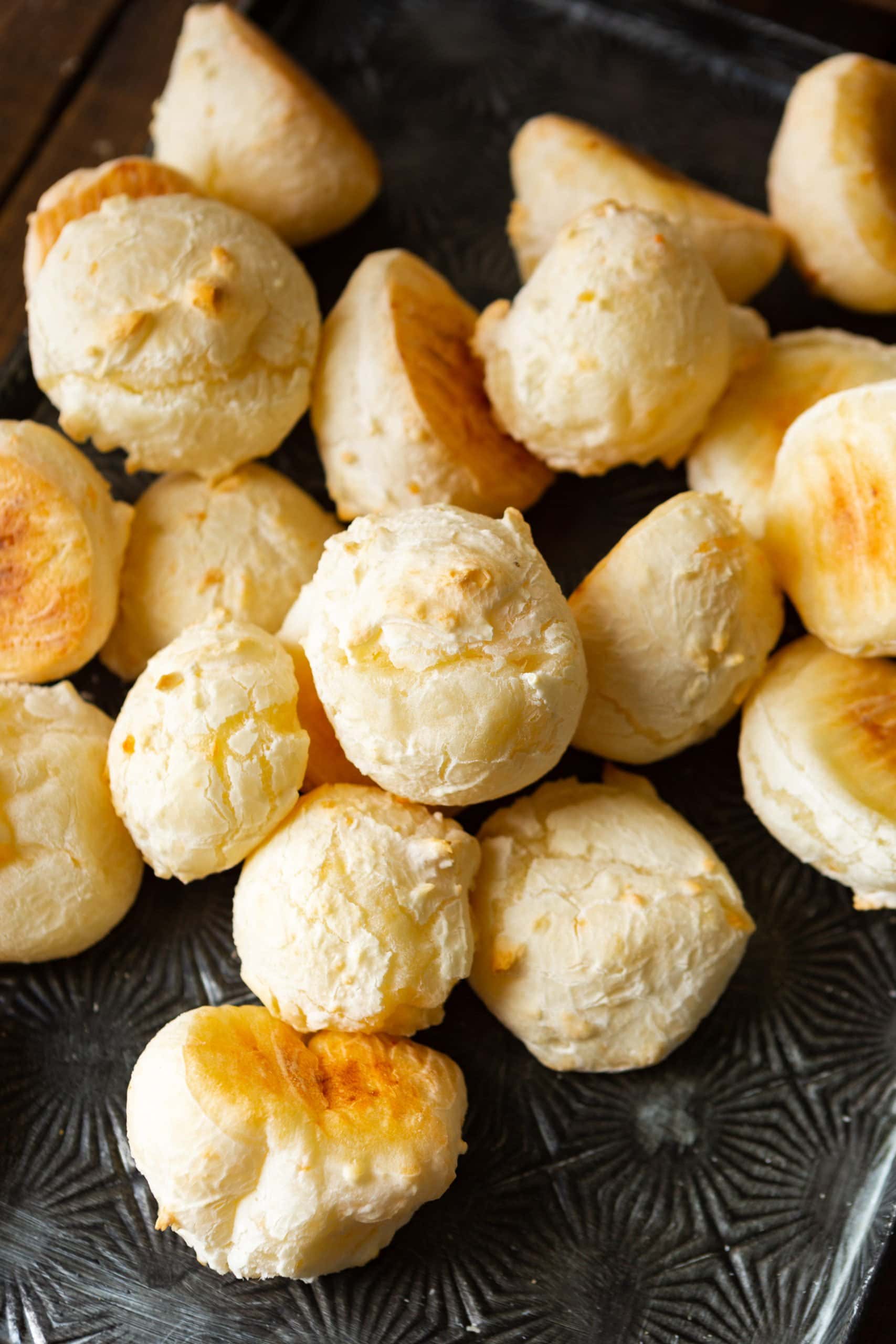 a photo of several small round cheese breads sitting on a dark wooden table.
