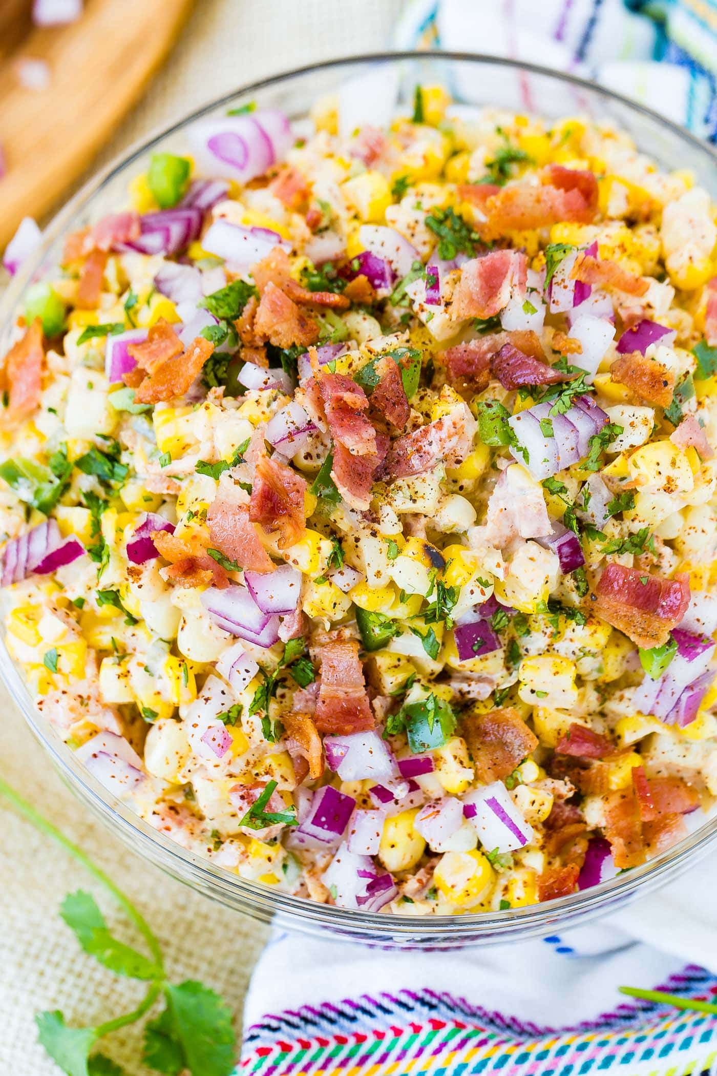 A bowl of Mexican corn salad topped with bacon and jalapeno.