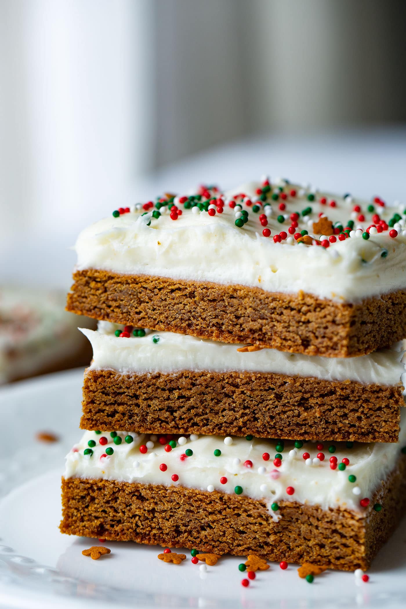 A photo of three gingerbread bars frosted with cream cheese frosting stacked on top of each other.