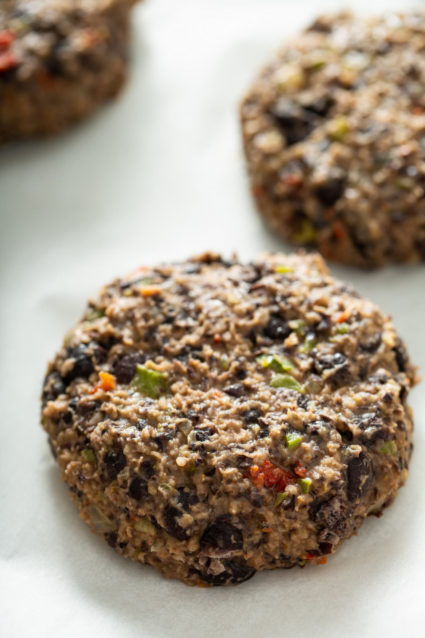 An uncooked black bean burger patty with another patty in the background.