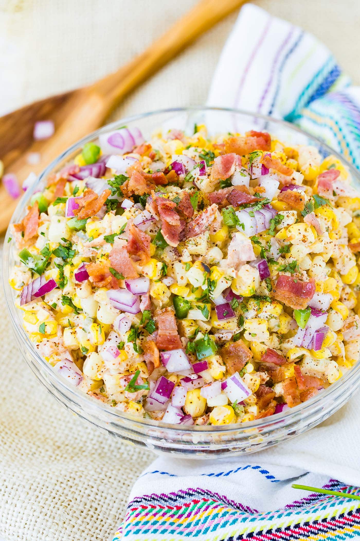 A bowl of Mexican corn salad topped with bacon and jalapeno.