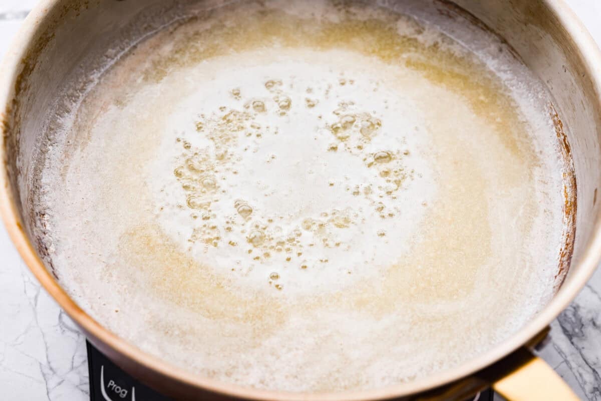 Skillet with butter and minced garlic cooking. 