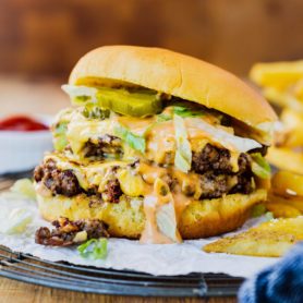 a photo of a double patty cheesy smash burger with shredded lettuce and pickles on a golden bun.