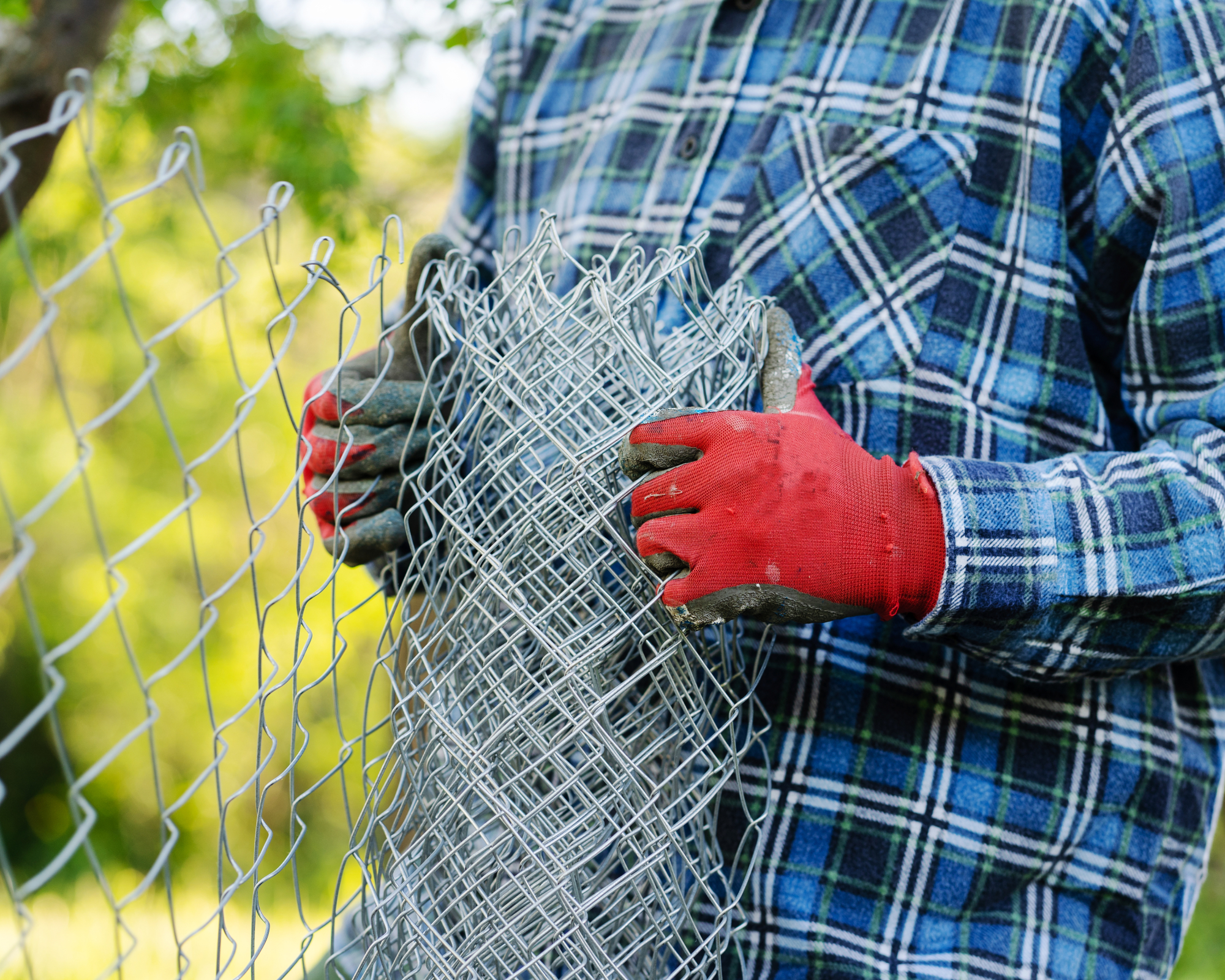Close up on midsection of unknown man holding protective chain link diamond wire fence in the field in day with copy space