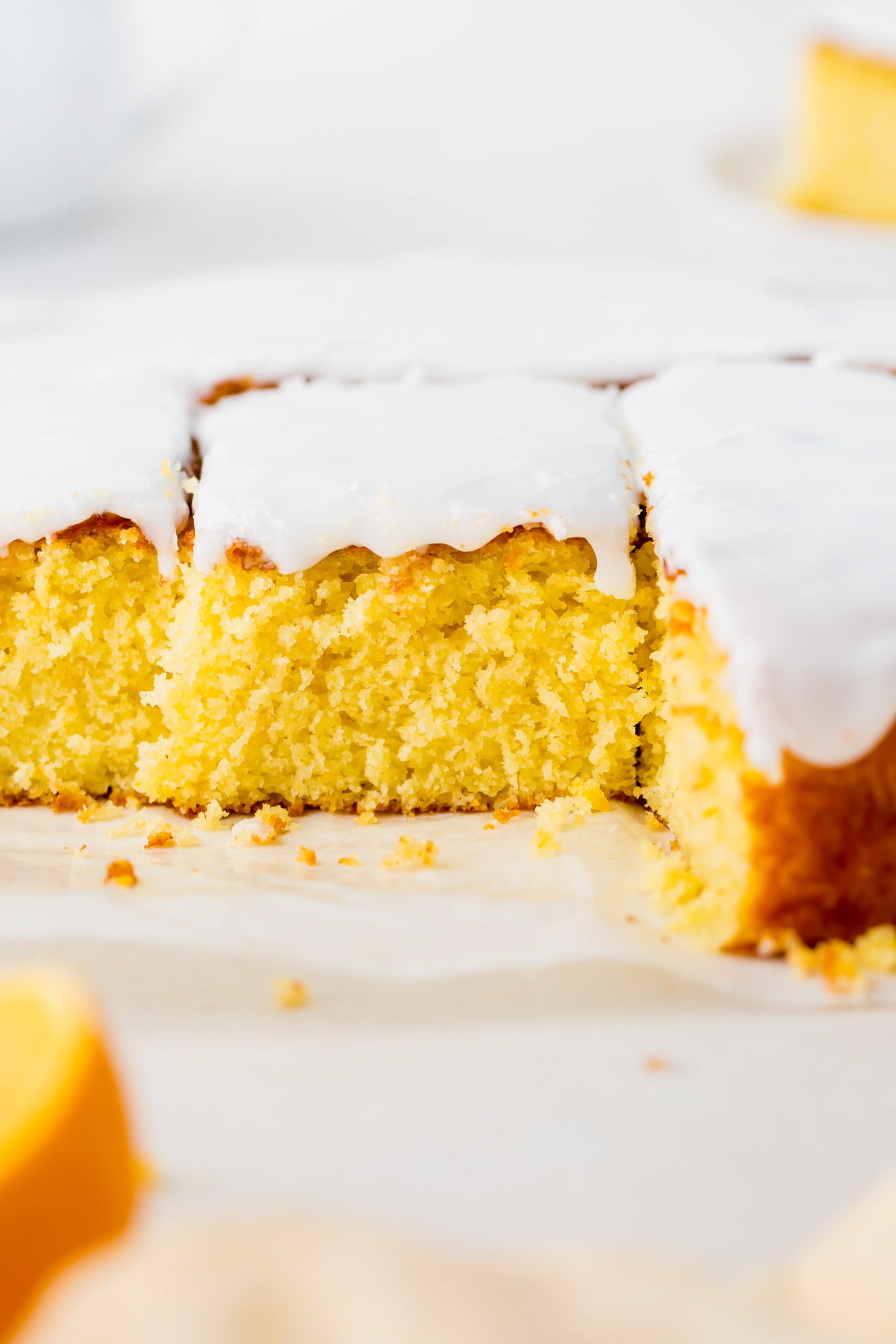 a photo of a lemon cake covered in white frosting. some pieces have been removed and the middle piece has been cut but not removed.