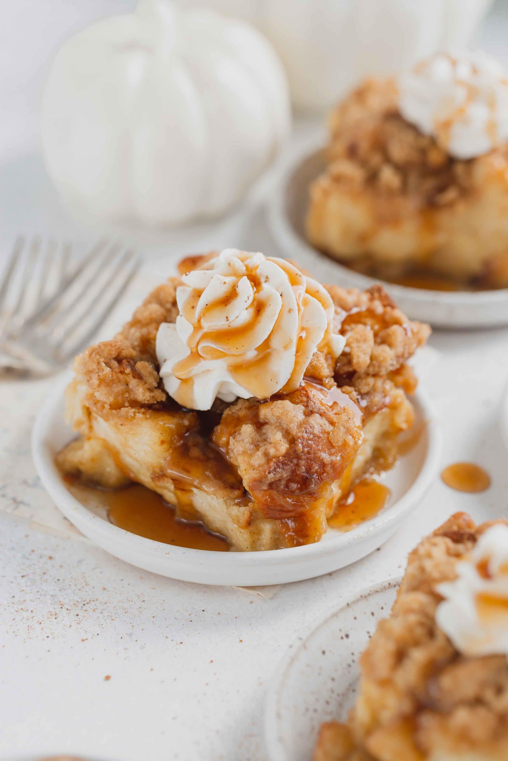 Eggnog french toast casserole on a serving plate. The french toast is topped with whipped cream and a little syrup.
