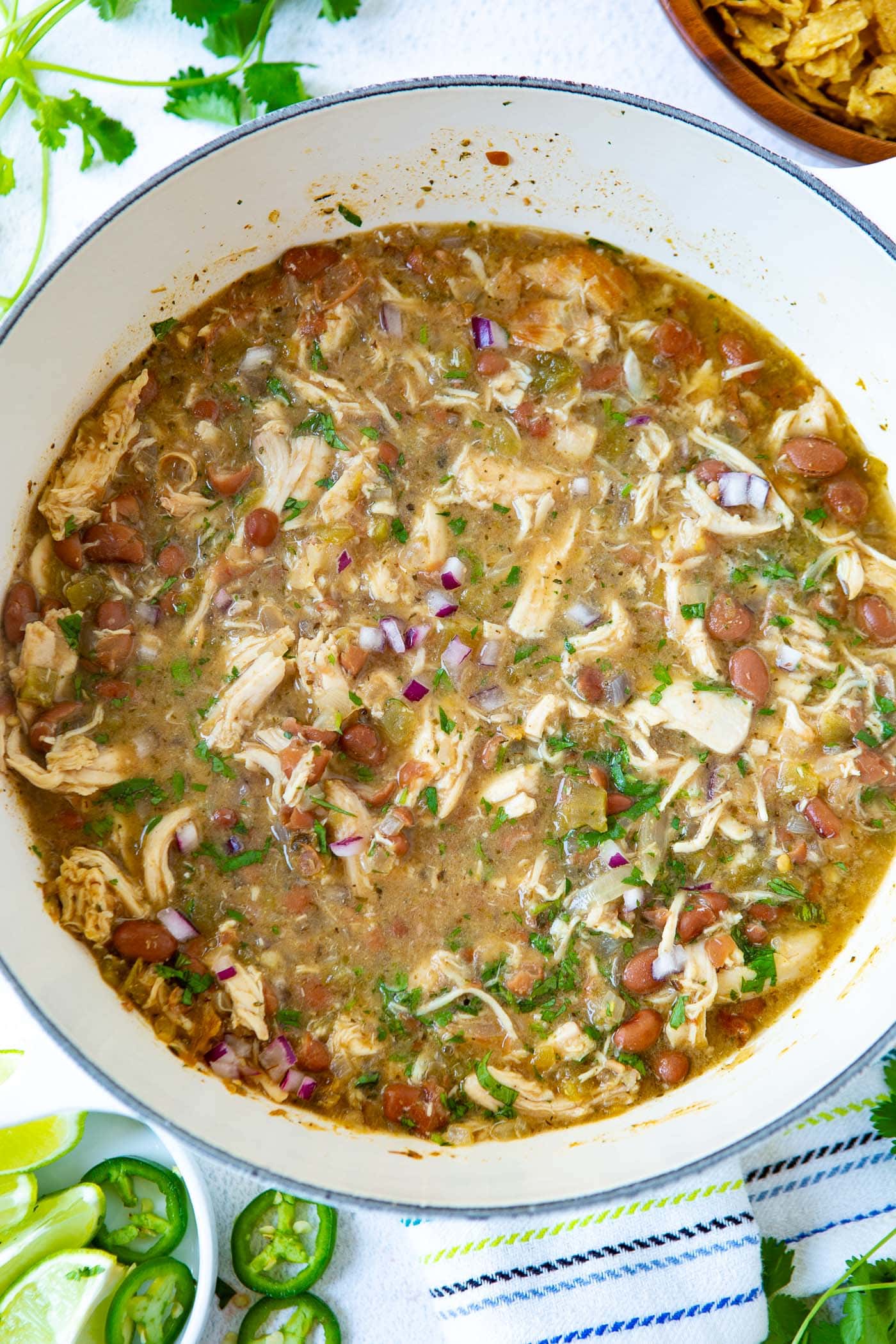 a pot of white chicken chili with rotisserie chicken, pinto beans, diced red onions and chopped fresh cilantro.