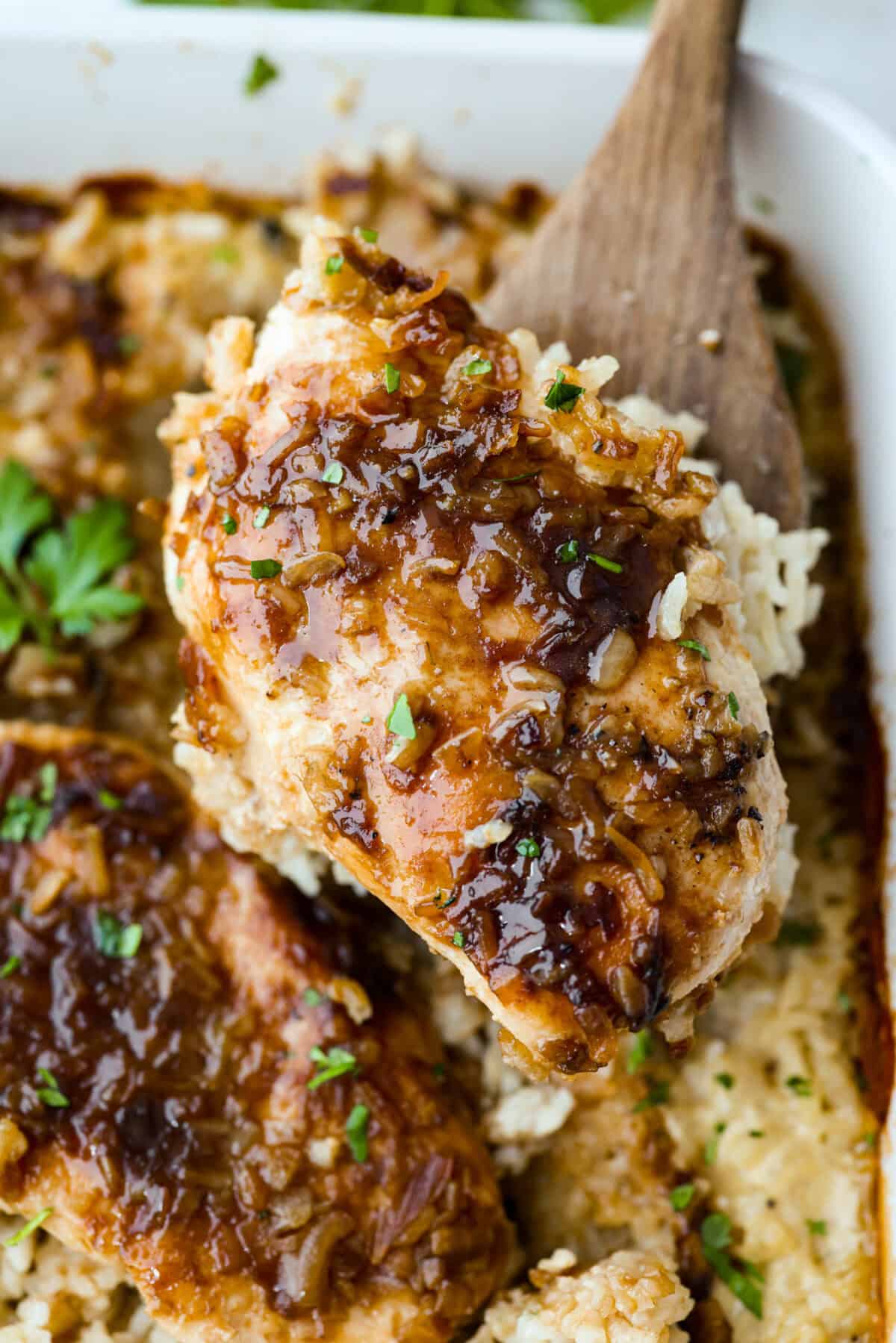 Close up shot of a no peek chicken and rice casserole serving being lifted with a spatula. 