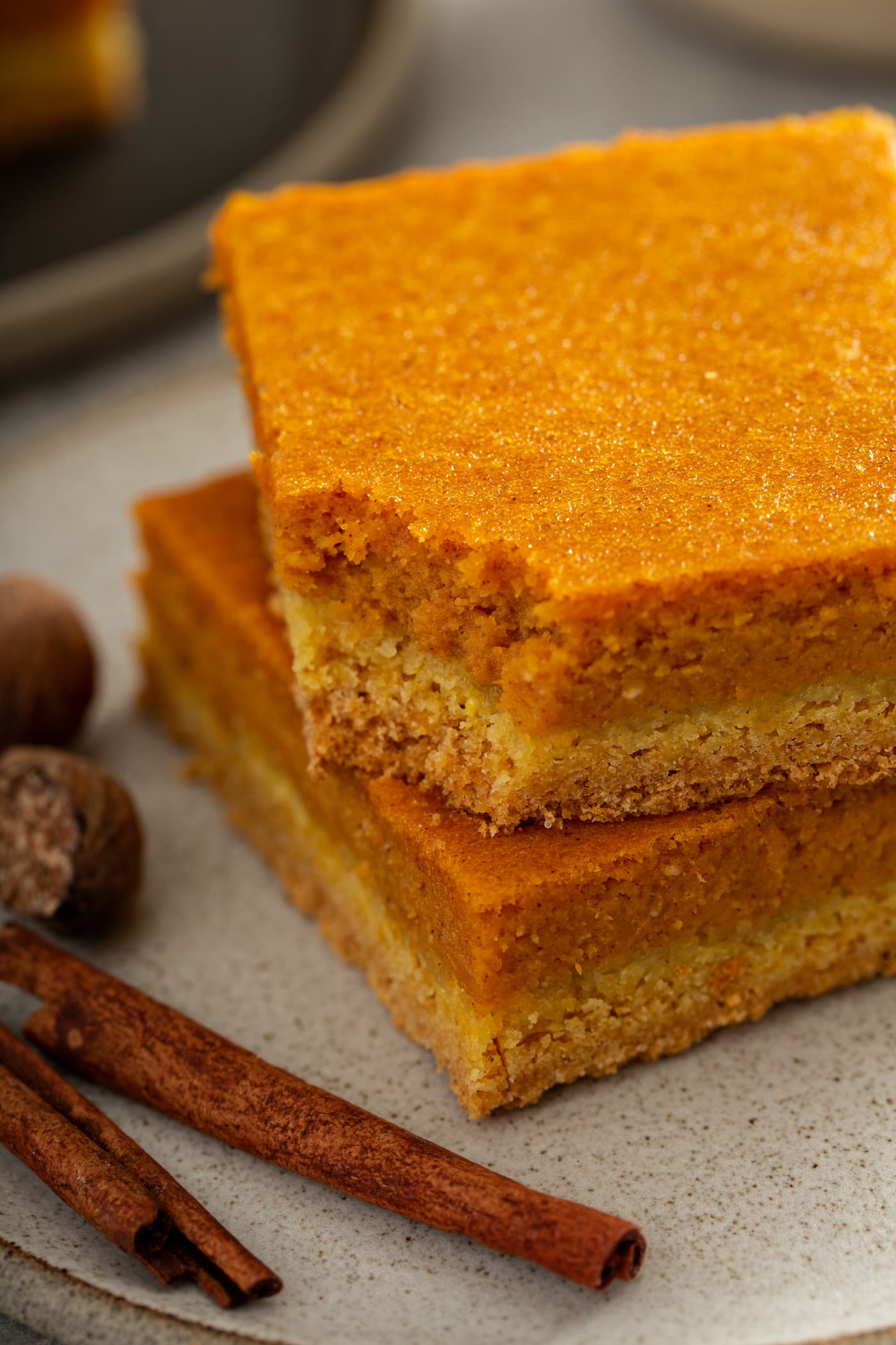 Two pieces of pumpkin gooey butter cake, stacked on top of each other.