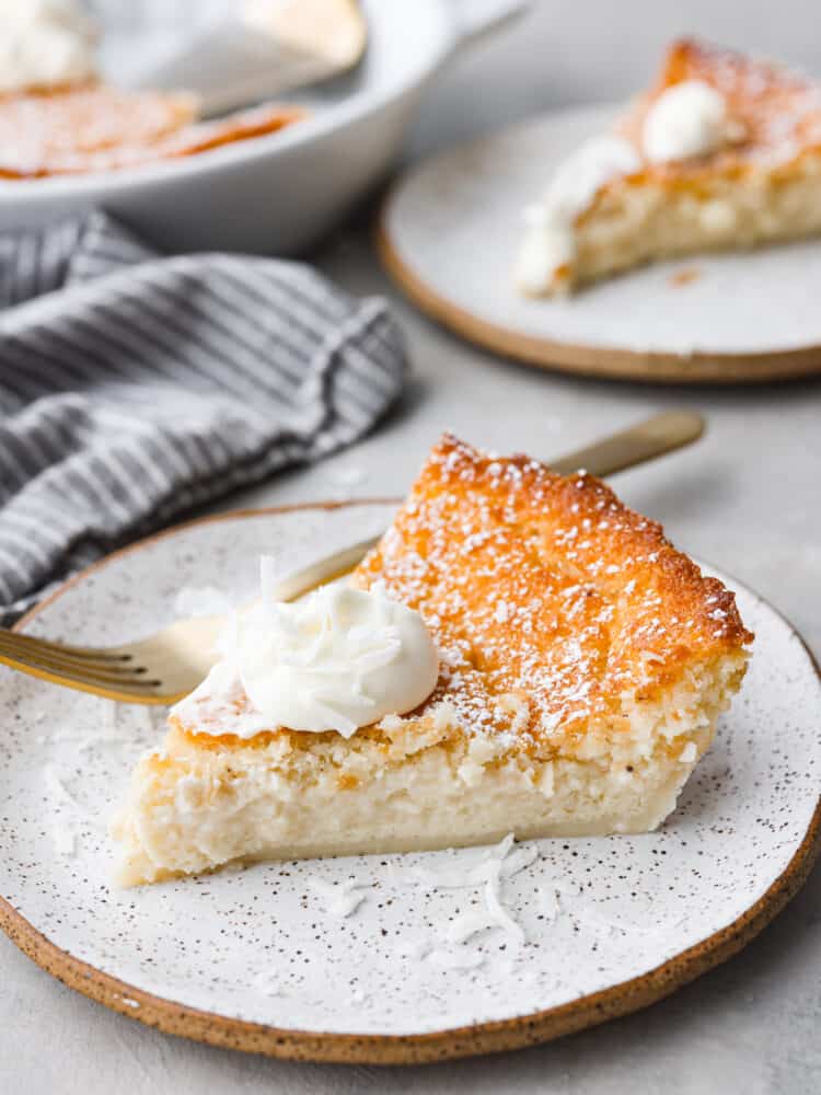 A slice of impossible pie topped with whipped cream on a stoneware plate.