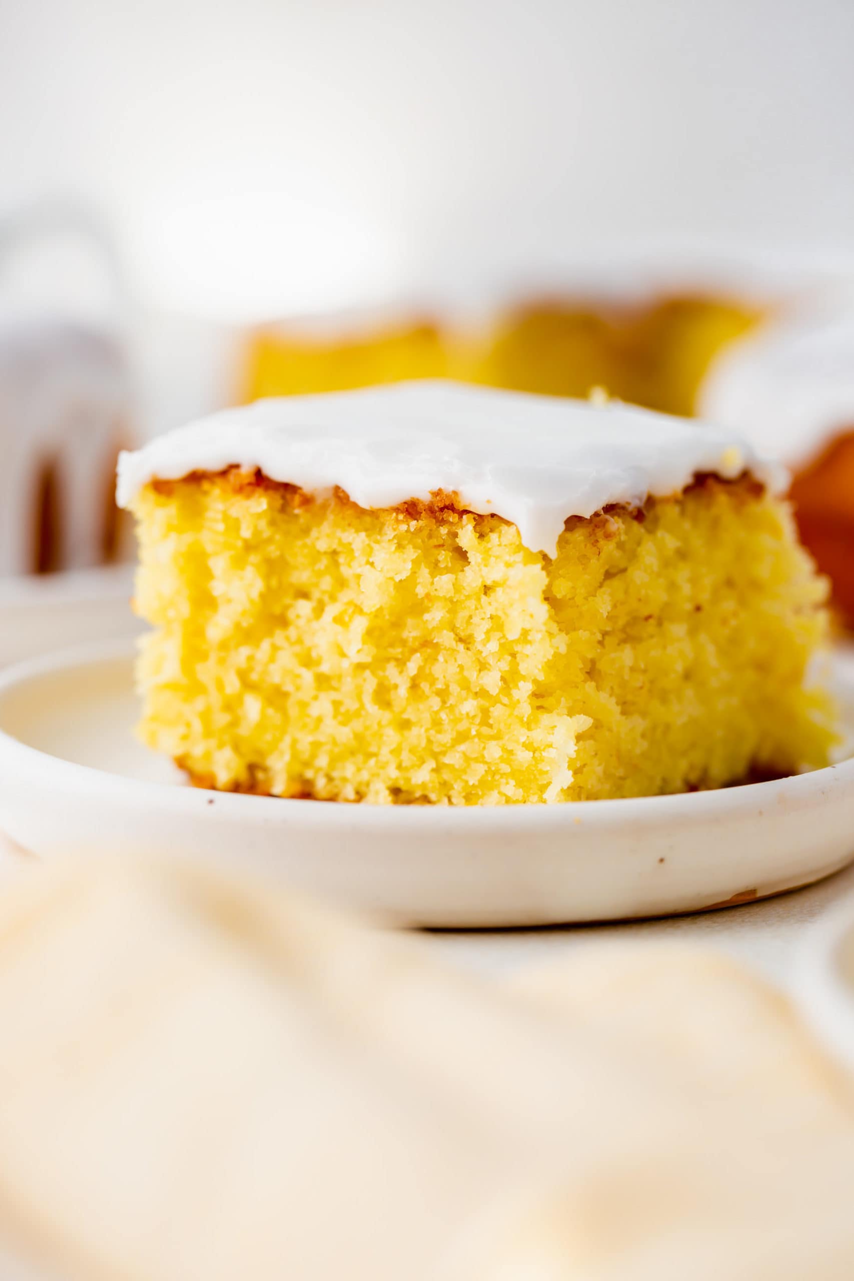 a photo of a piece of glazed lemon cake sitting on a white plate