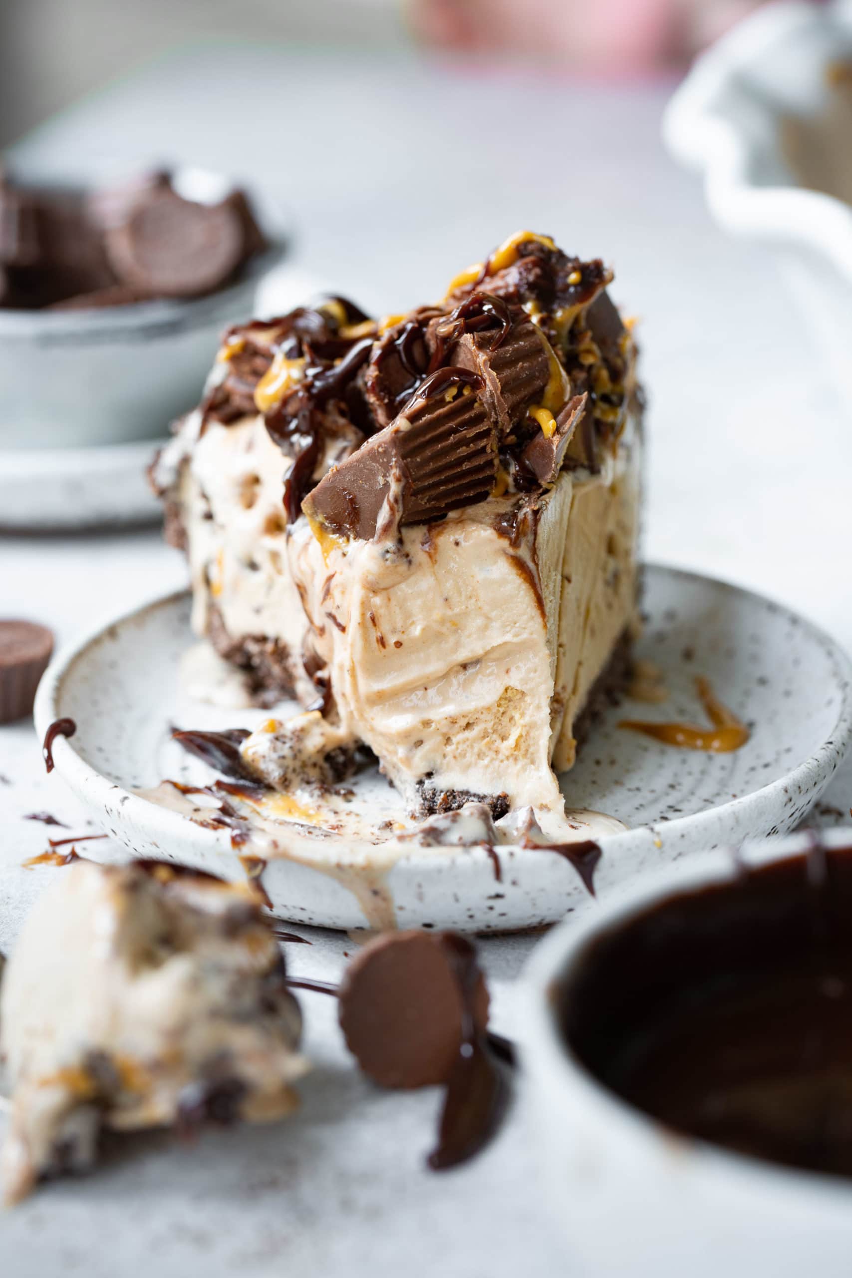 a photo of a slice of reeses ice cream pie with a bite taken out of it sitting on a small saucer.