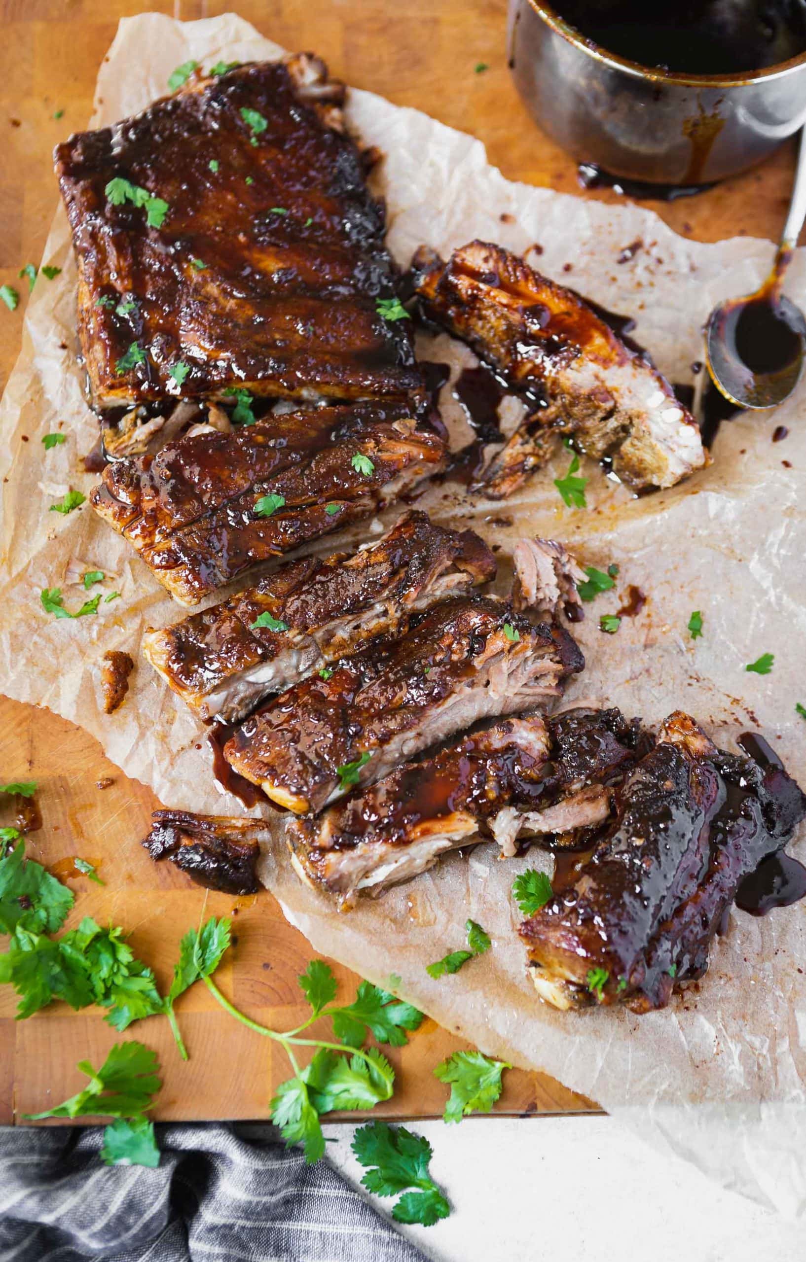 a photo of a rack of asian sticky ribs that have been cut apart into individual ribs all sitting on a piece of parchment paper.