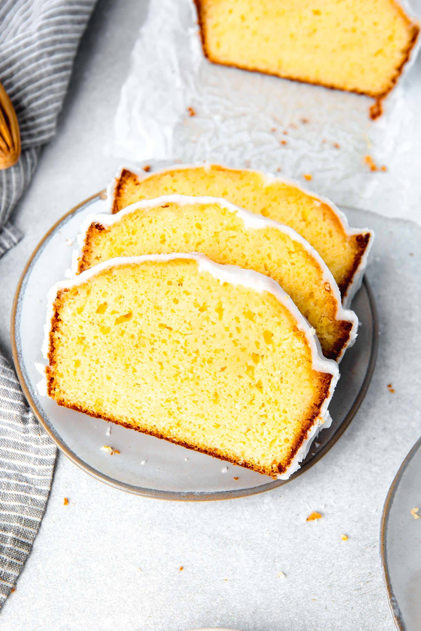 a photo of three slices of lemon loaf cake laying on a white plate.