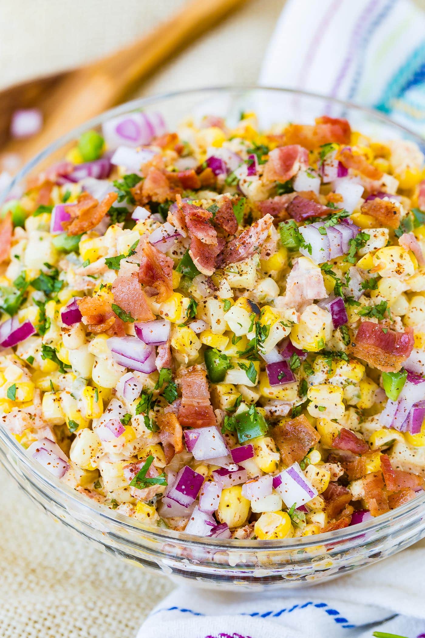 A bowl of Mexican corn salad topped with bacon and jalapeno.