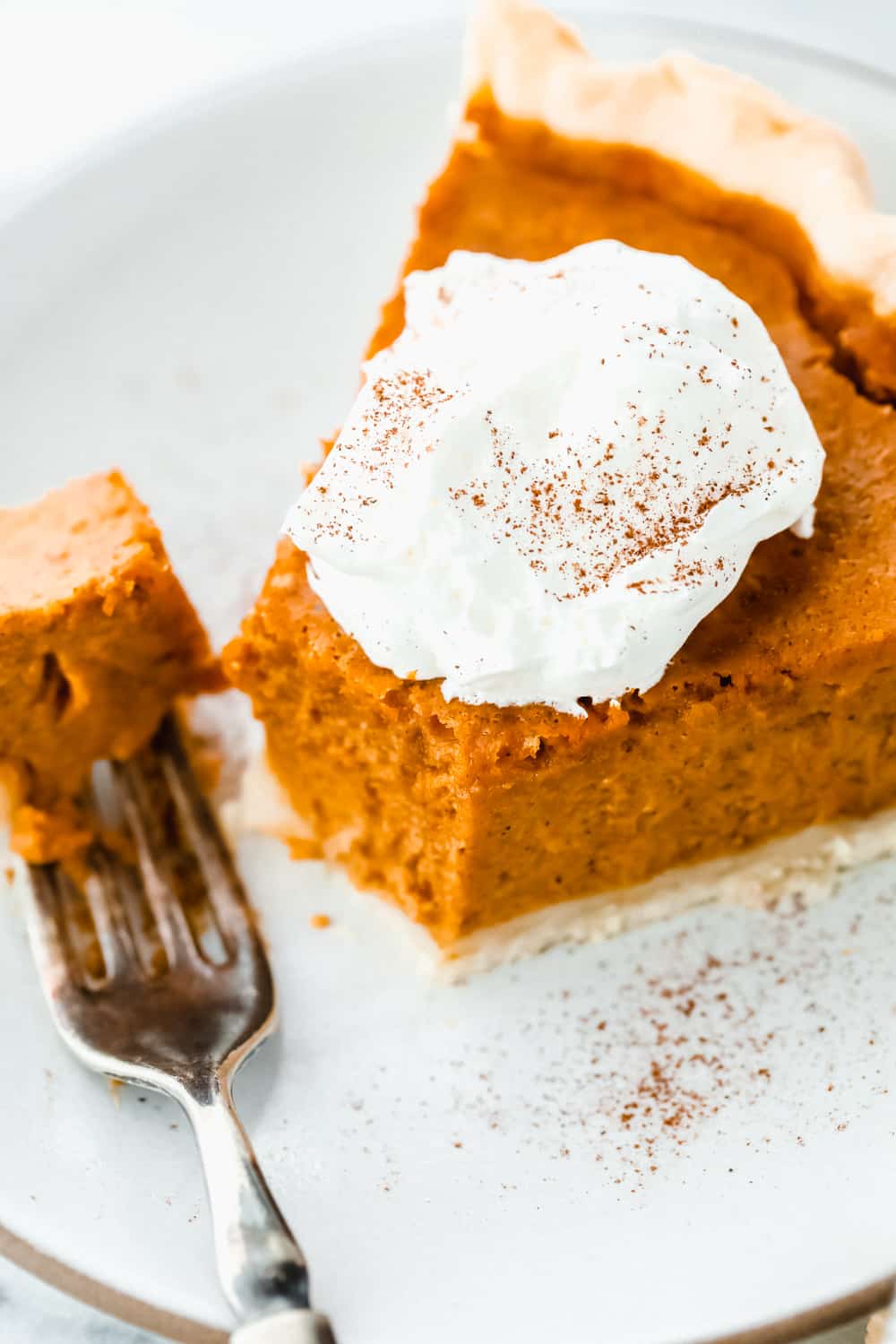 A sliced piece of pumpkin pie with a fork. 