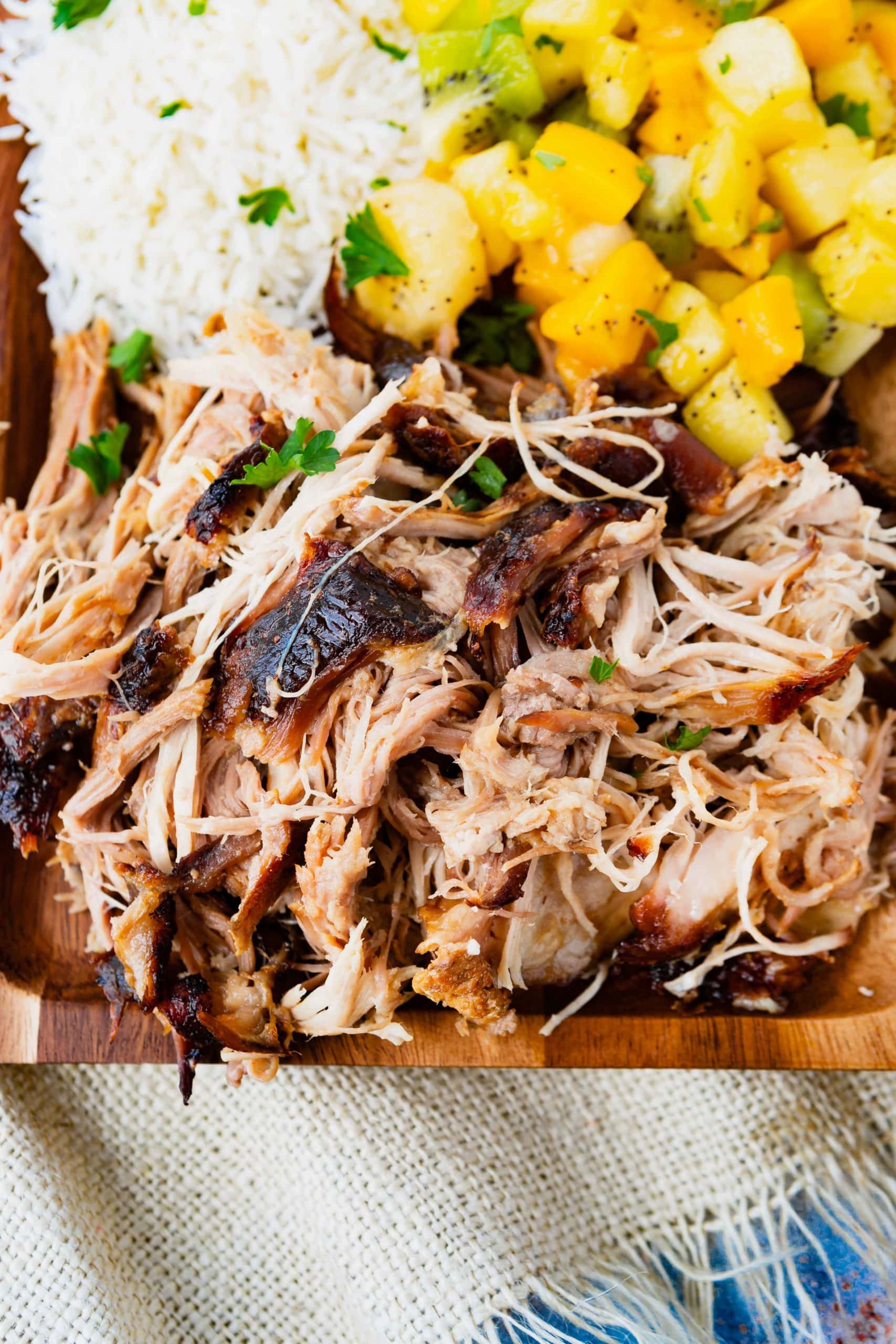 a photo of tender, juicy kalua pulled pork on a wooden serving platter 