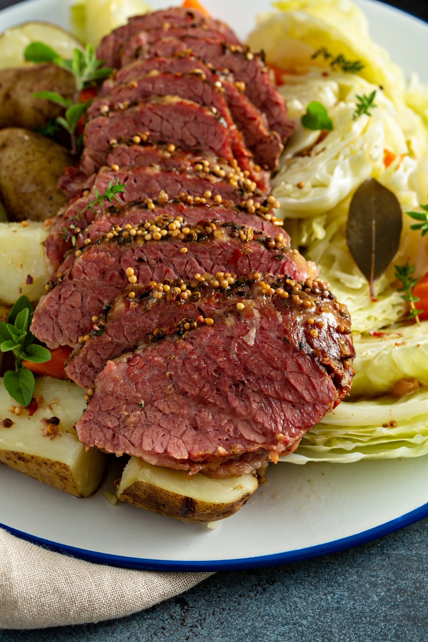 Sliced corned beef laying on top of potatoes, carrots and cabbage.