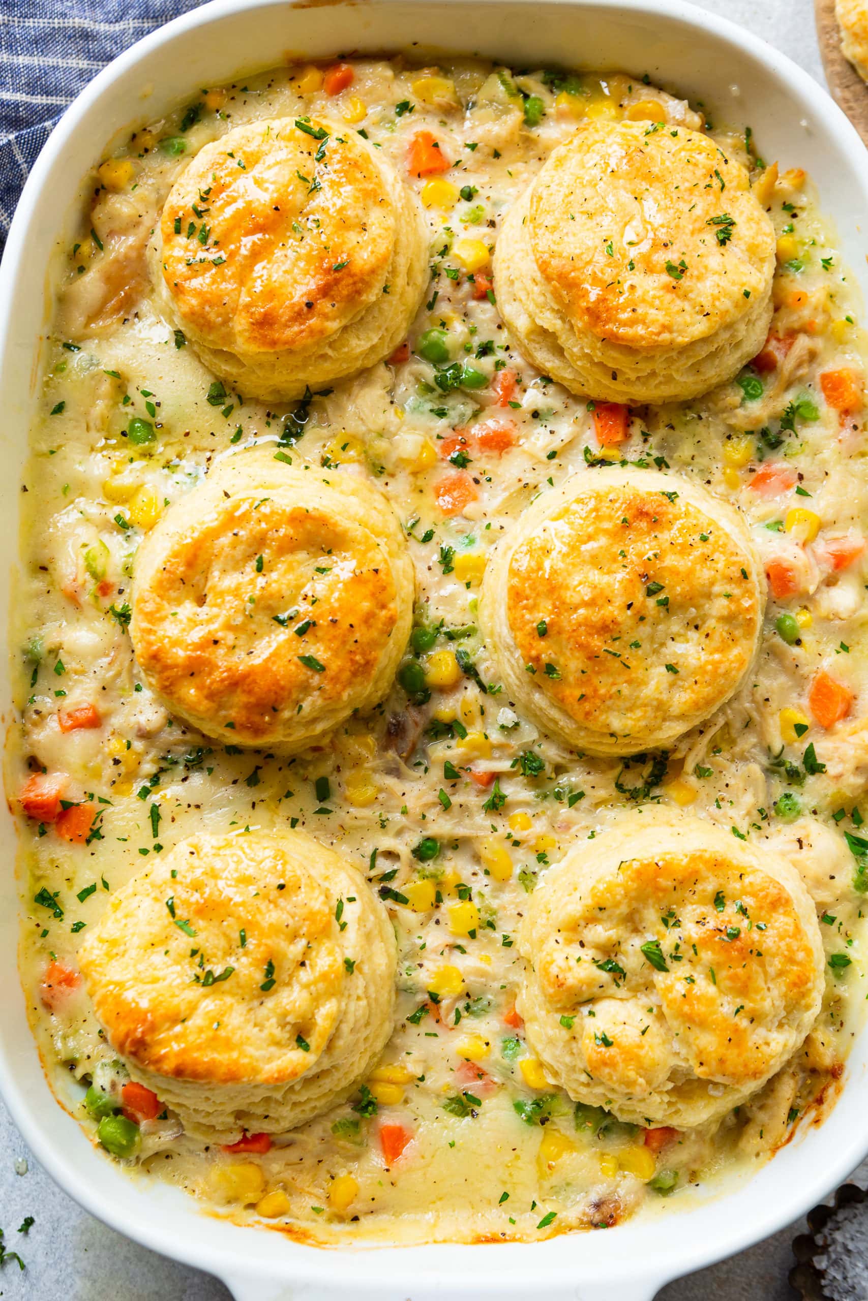 a photo of a rectangular baking dish full of creamy chicken pot pie filling topped with golden baked buttermilk biscuits.