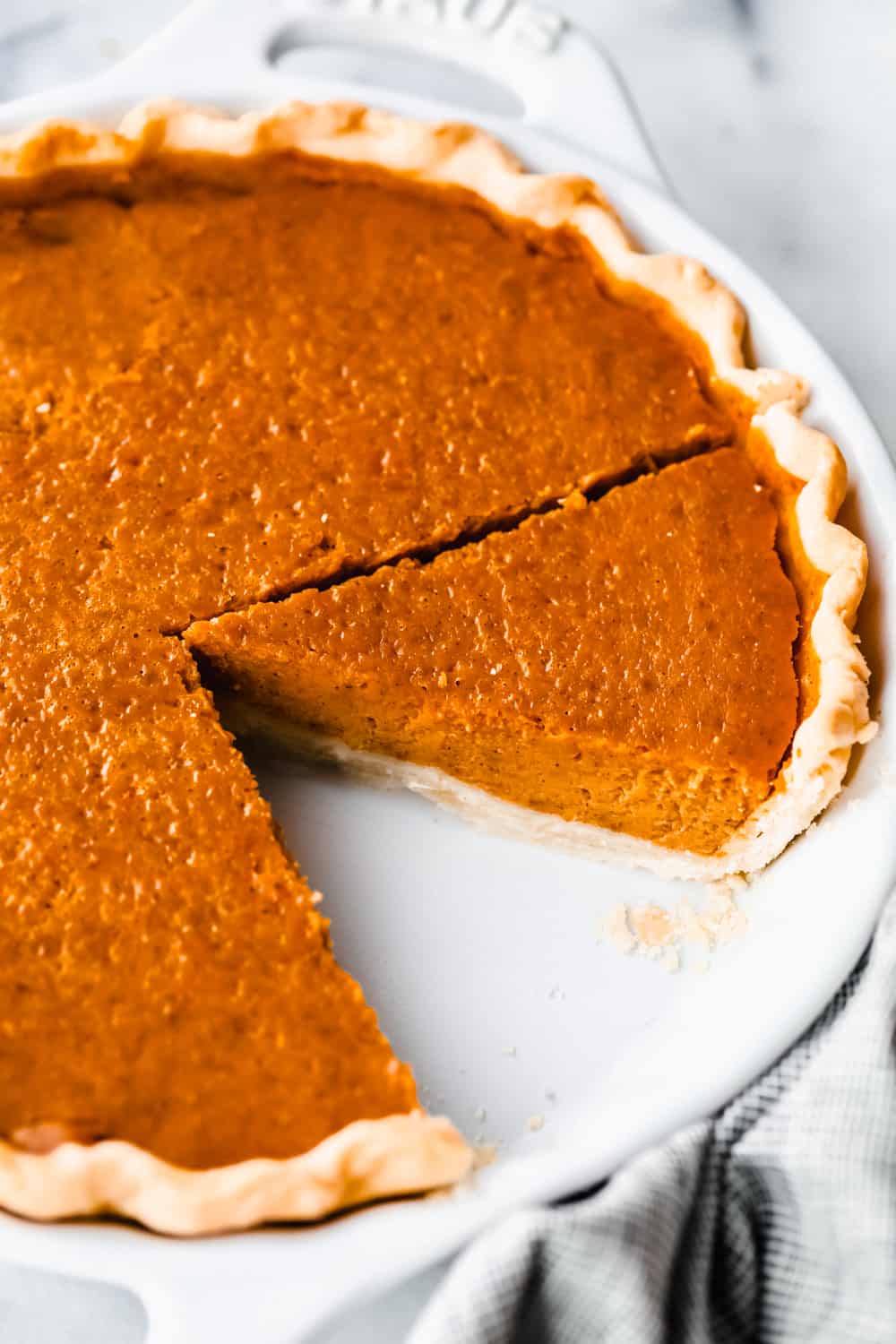 Pumpkin pie baked with a slice taken out of the pan. 