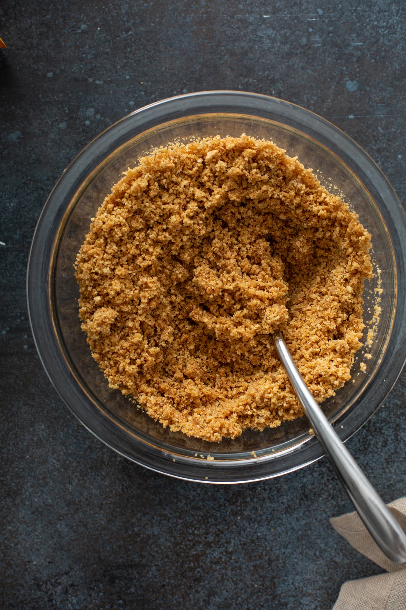 A bowl of graham cracker crumbs with a spoon in it.