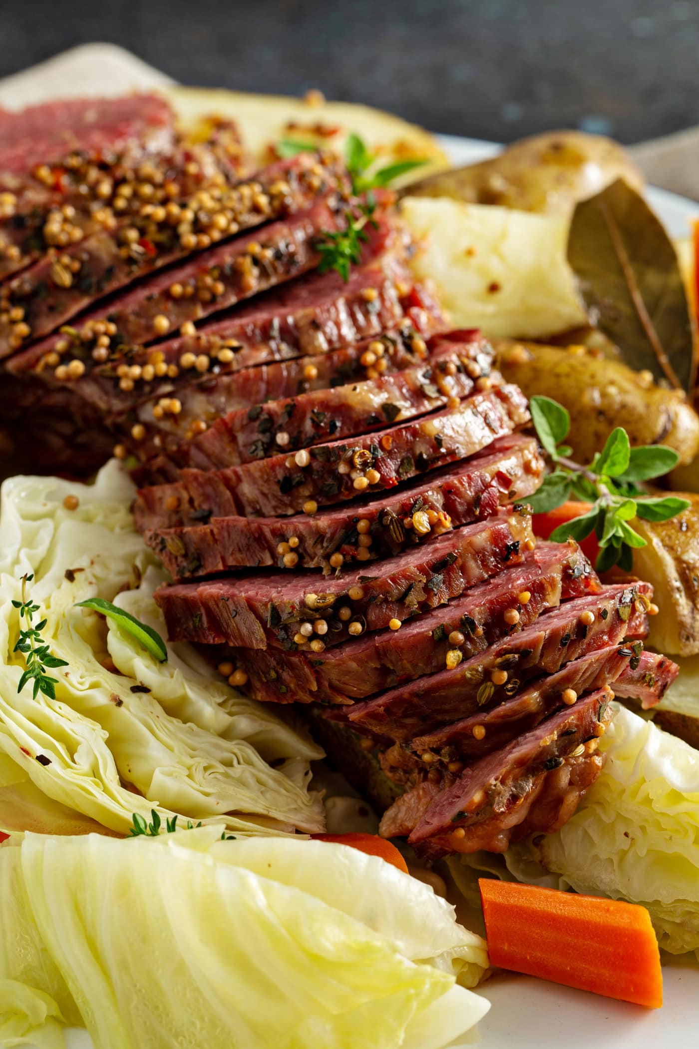 Sliced corned beef resting on top of potatoes and cabbage.