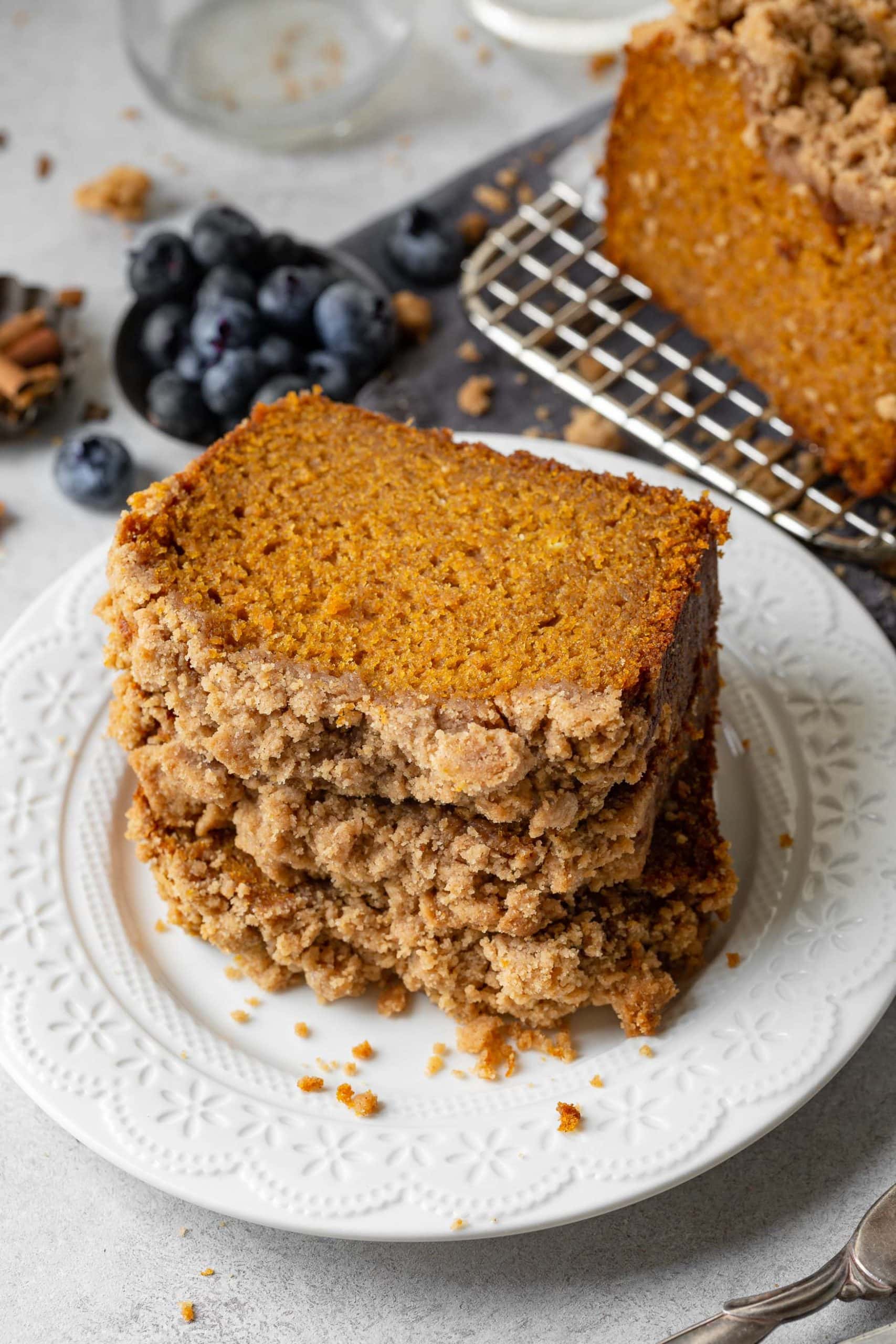 a photo of a stack of thick slices of moist pumpkin bread topped with cinnamon streusel topping.