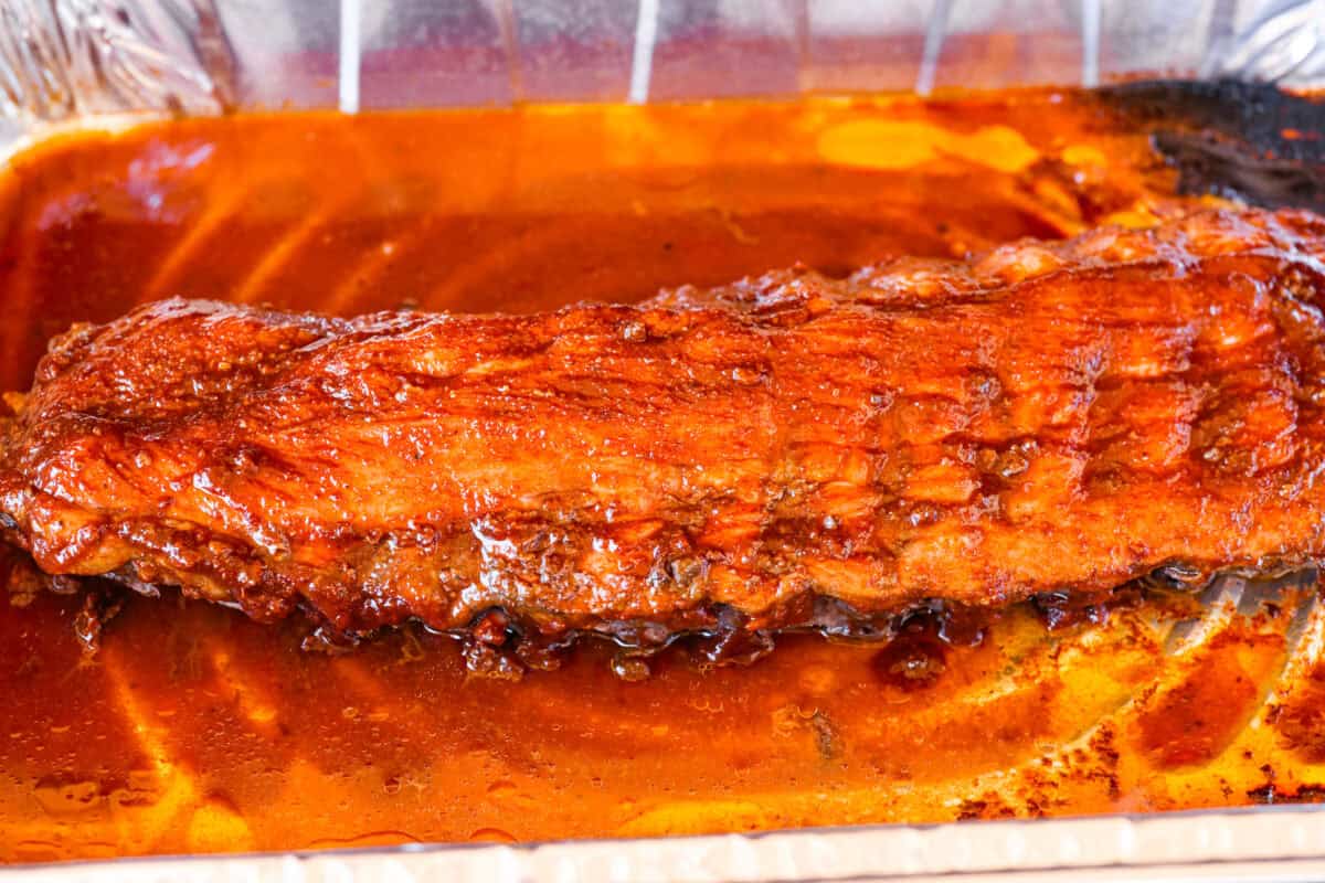 Partially cooked ribs with sauce spread all over them.