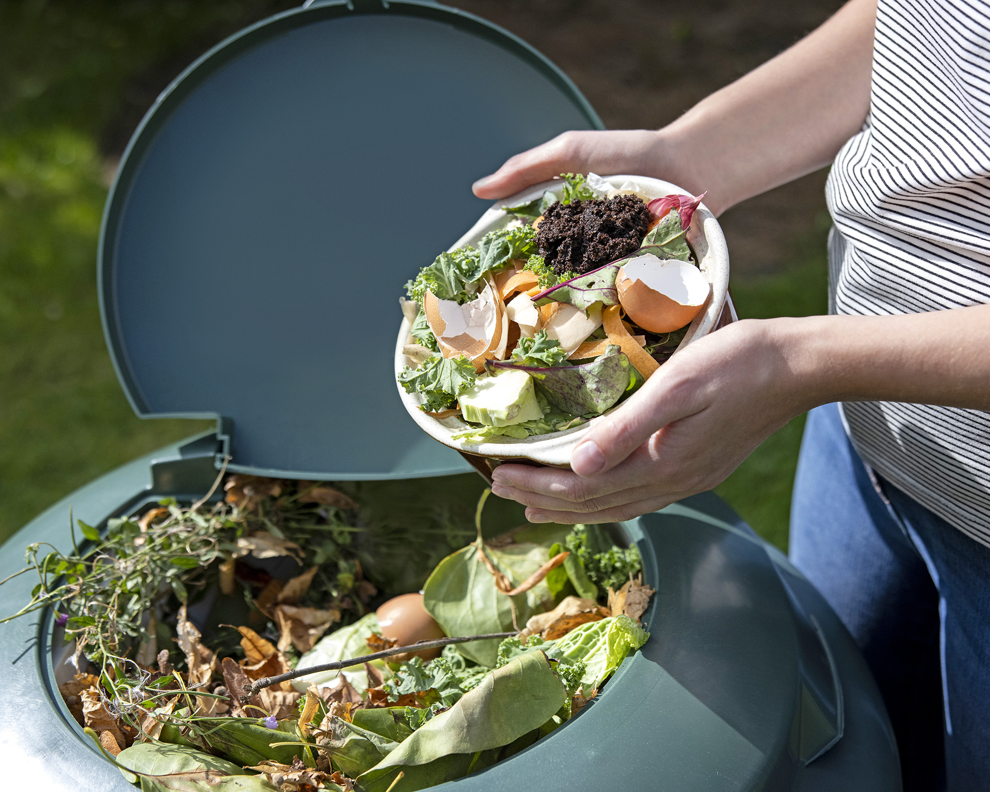 Adding kitchen scraps to compost bin