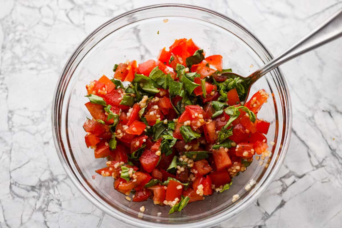 Fresh bruschetta ingredients mixed together in a bowl. 