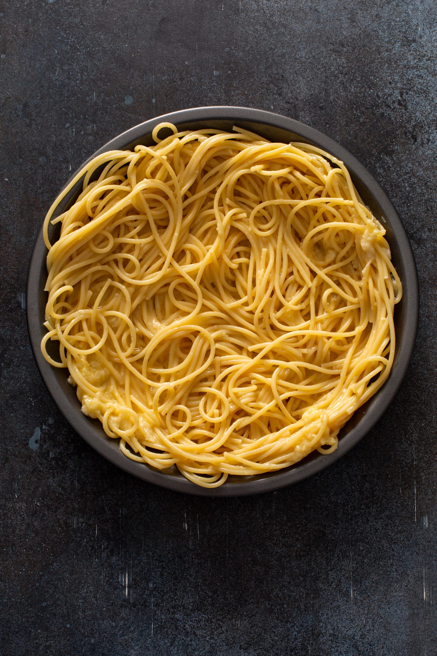 A pie dish filled with cooked spaghetti noodles.