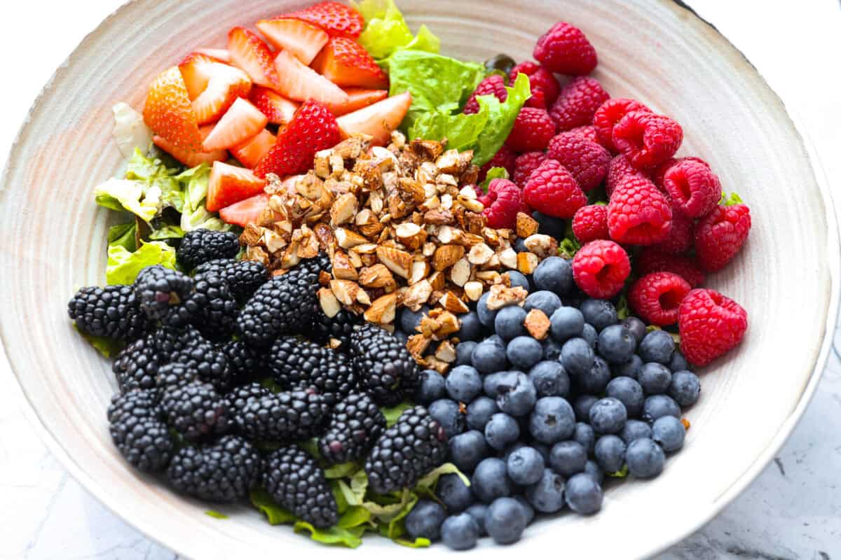 Large bowl with salad ingredients added to it. 
