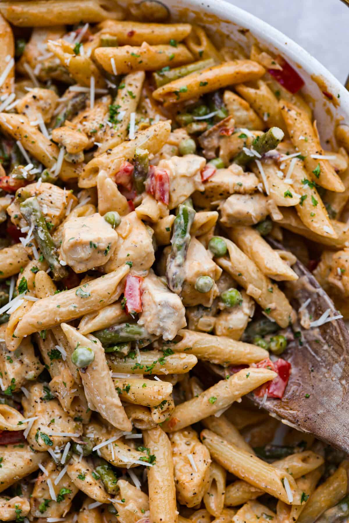 Closeup of the chipotle pasta being stirred with a wooden spoon.
