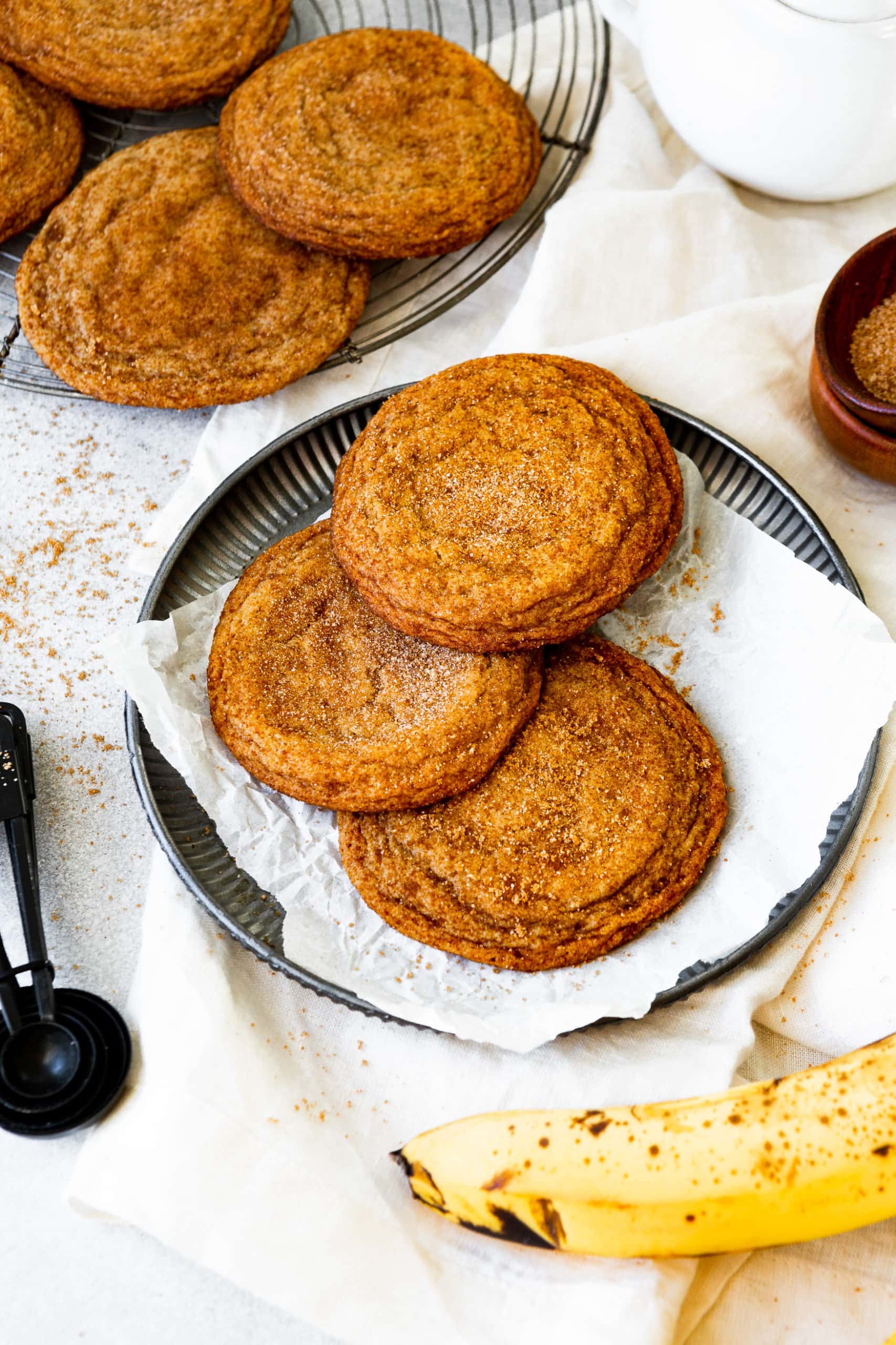 a photo of three perfectly baked golden banana cookies sitting on a white napkin on a small gray saucer.