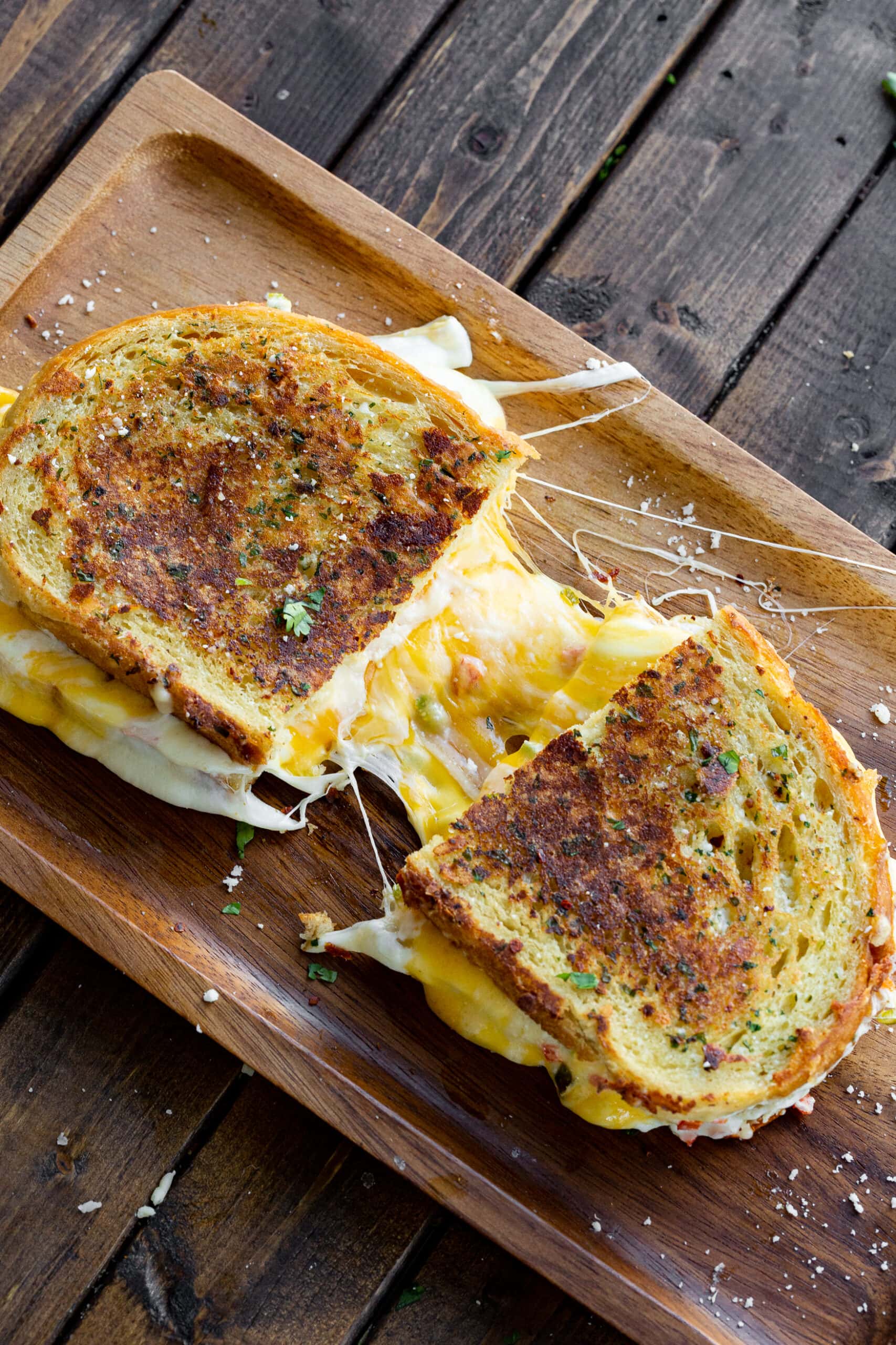 a photo of a golden grilled cheese sandwich that has been sliced in half and pulled apart slightly to show the melted cheese inside.