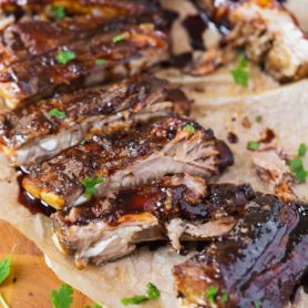 a photo of a rack of asian sticky ribs that have been all cut apart topped with sesame seeds and chopped cilantro.
