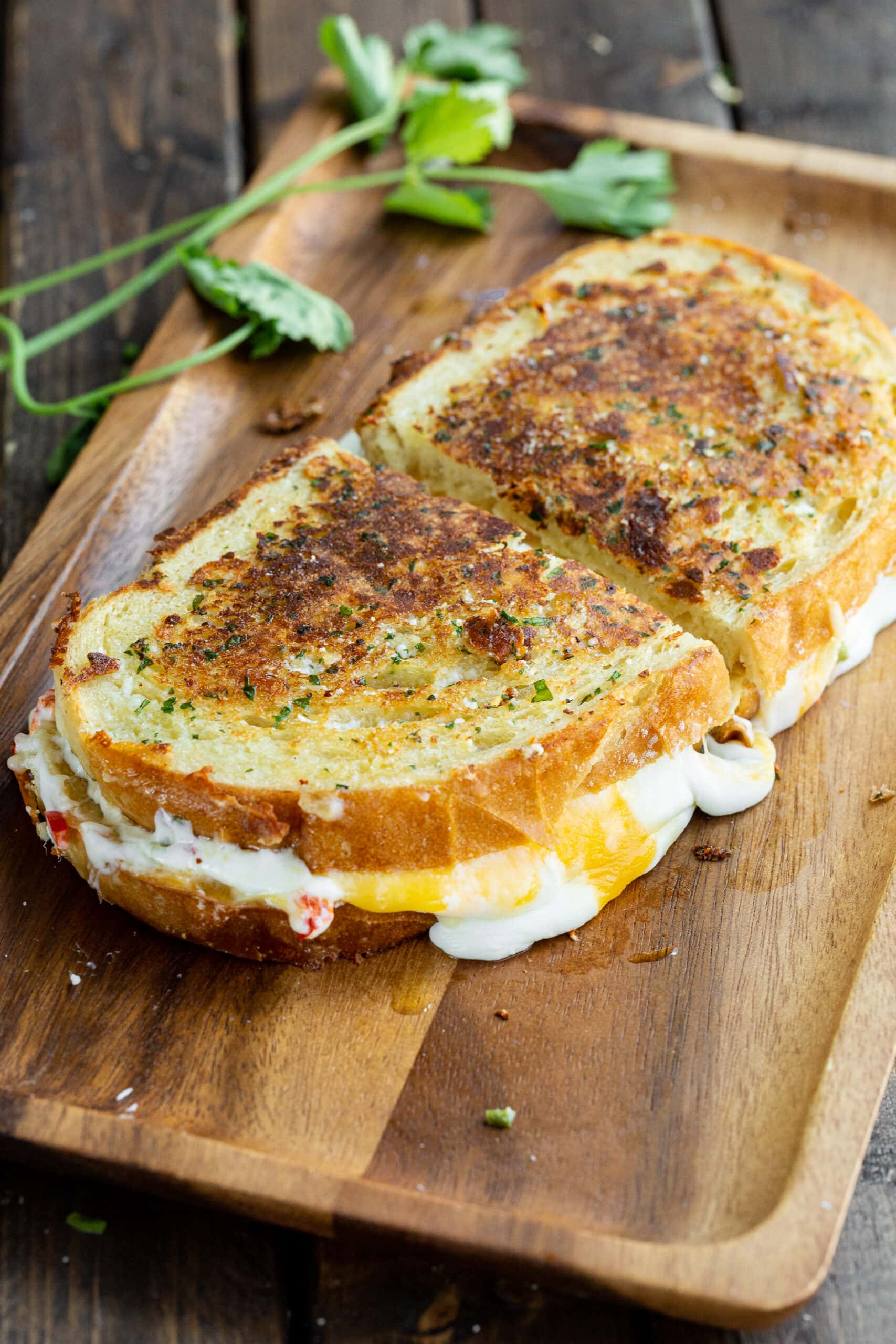 a photo of a perfectly golden grilled cheese sandwich with melted orange and white cheeses oozing out the sides of the sandwich which has been cut in half.