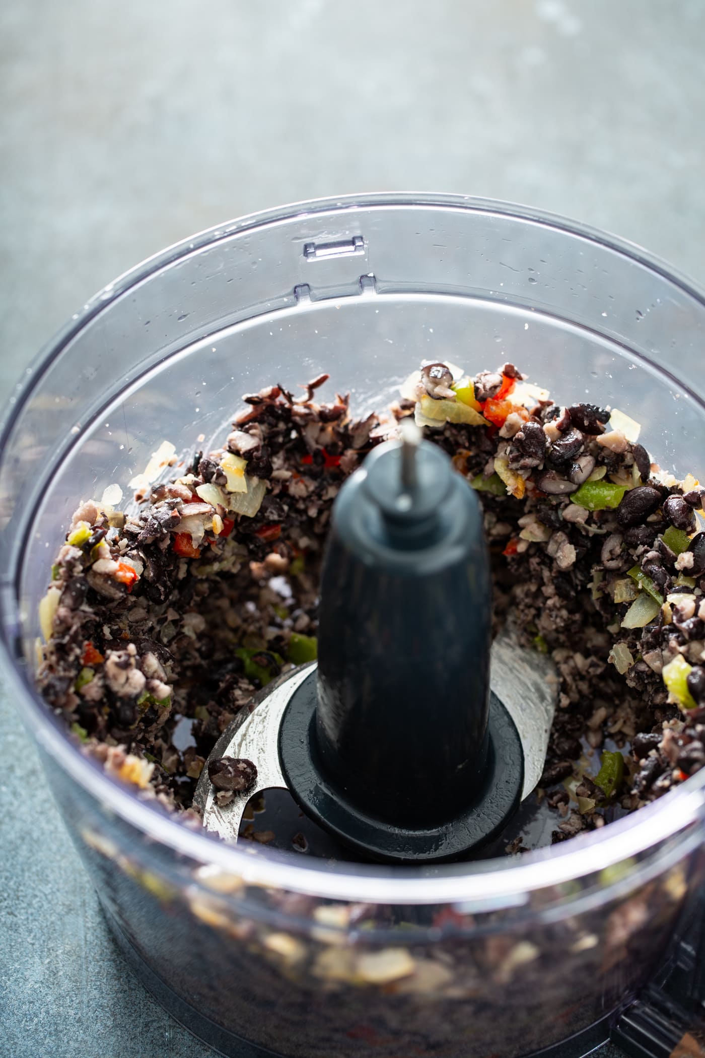 A food processor with ground black beans and peppers.