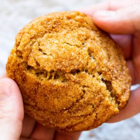 a photo of someone holding a golden banana cookie and breaking it in half.