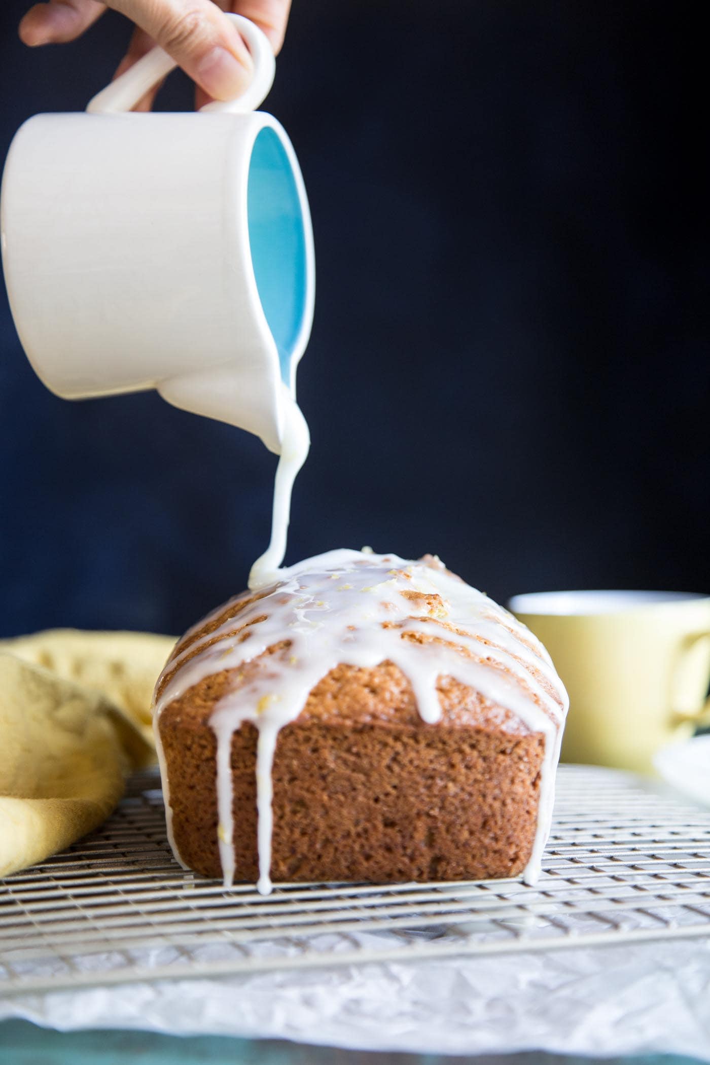 Pouring lemon glaze over lemon zucchini bread