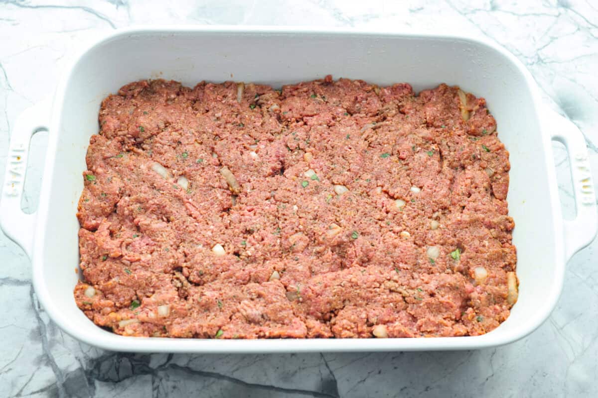 Meatloaf ingredients pressed into the bottom of the baking dish. 