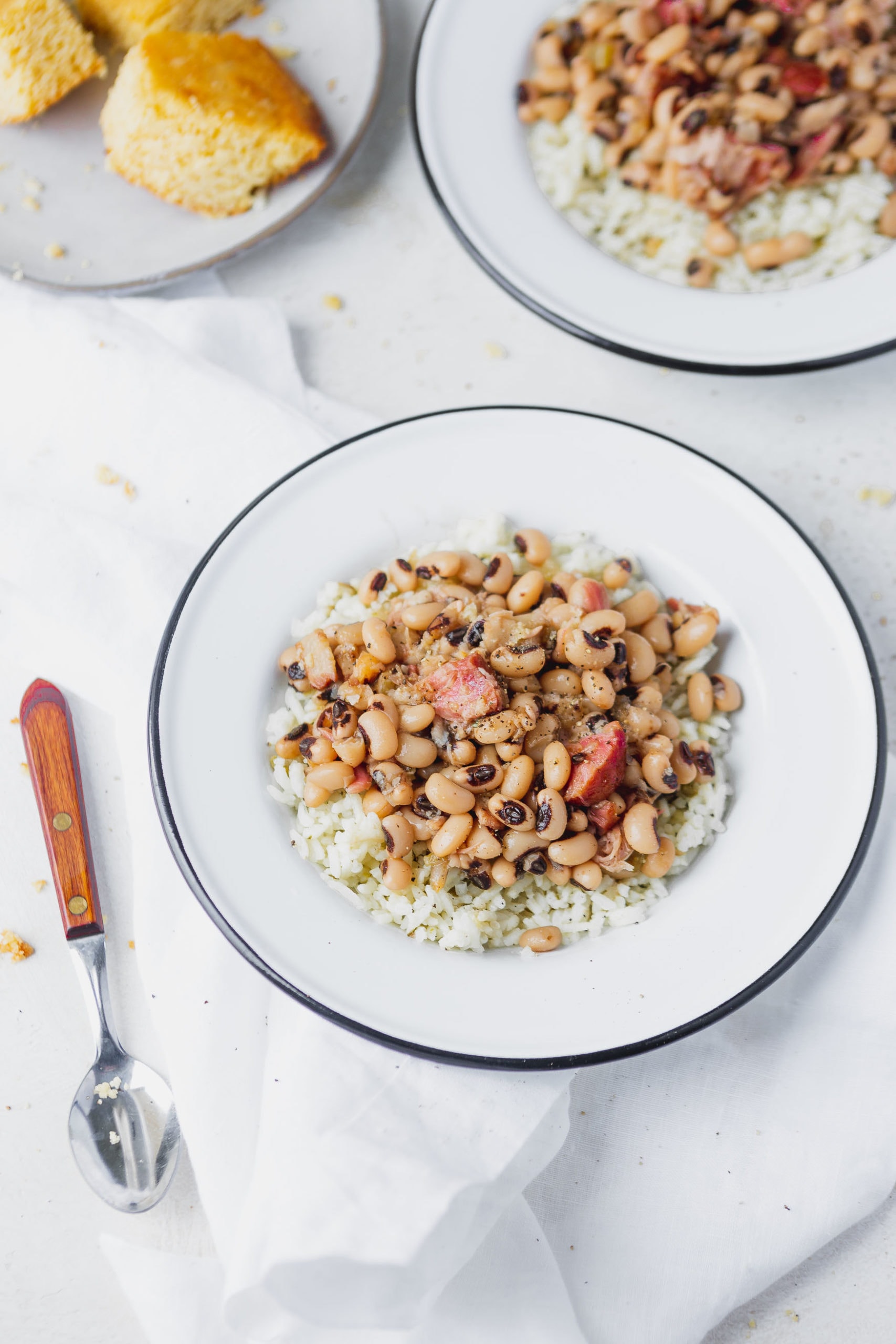 A white plate with instant pot black eyed beans over rice. A spoon is next to the plate.