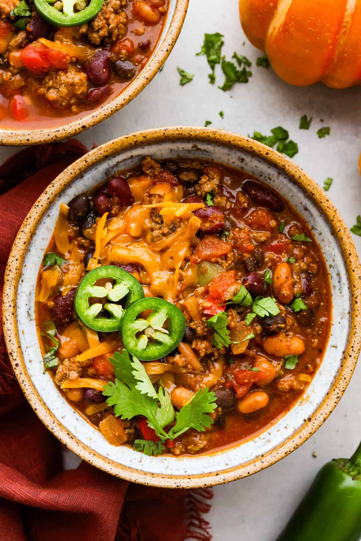 Pumpkin chili in a small bowl, topped with cheese and sliced jalapenos.