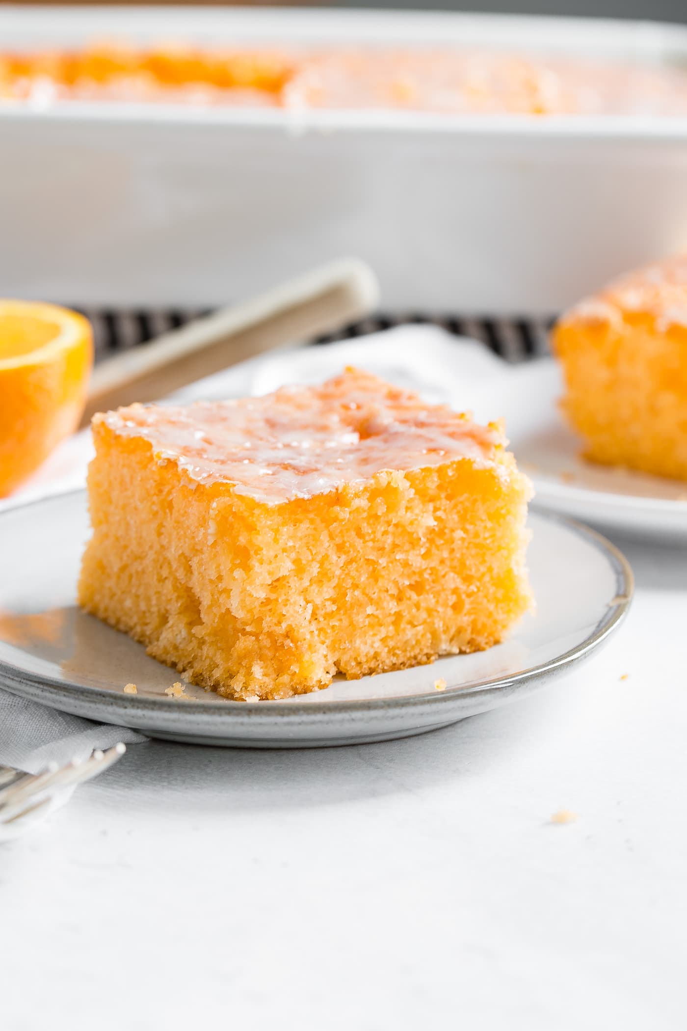A photo of a piece of orange jello cake on a small white plate.