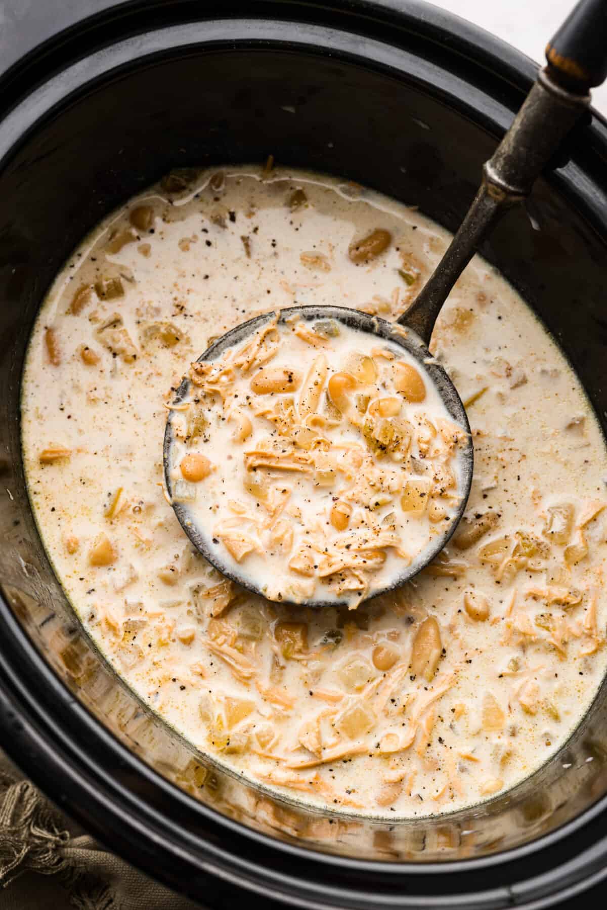 White chicken chili in a crockpot with a ladle. 