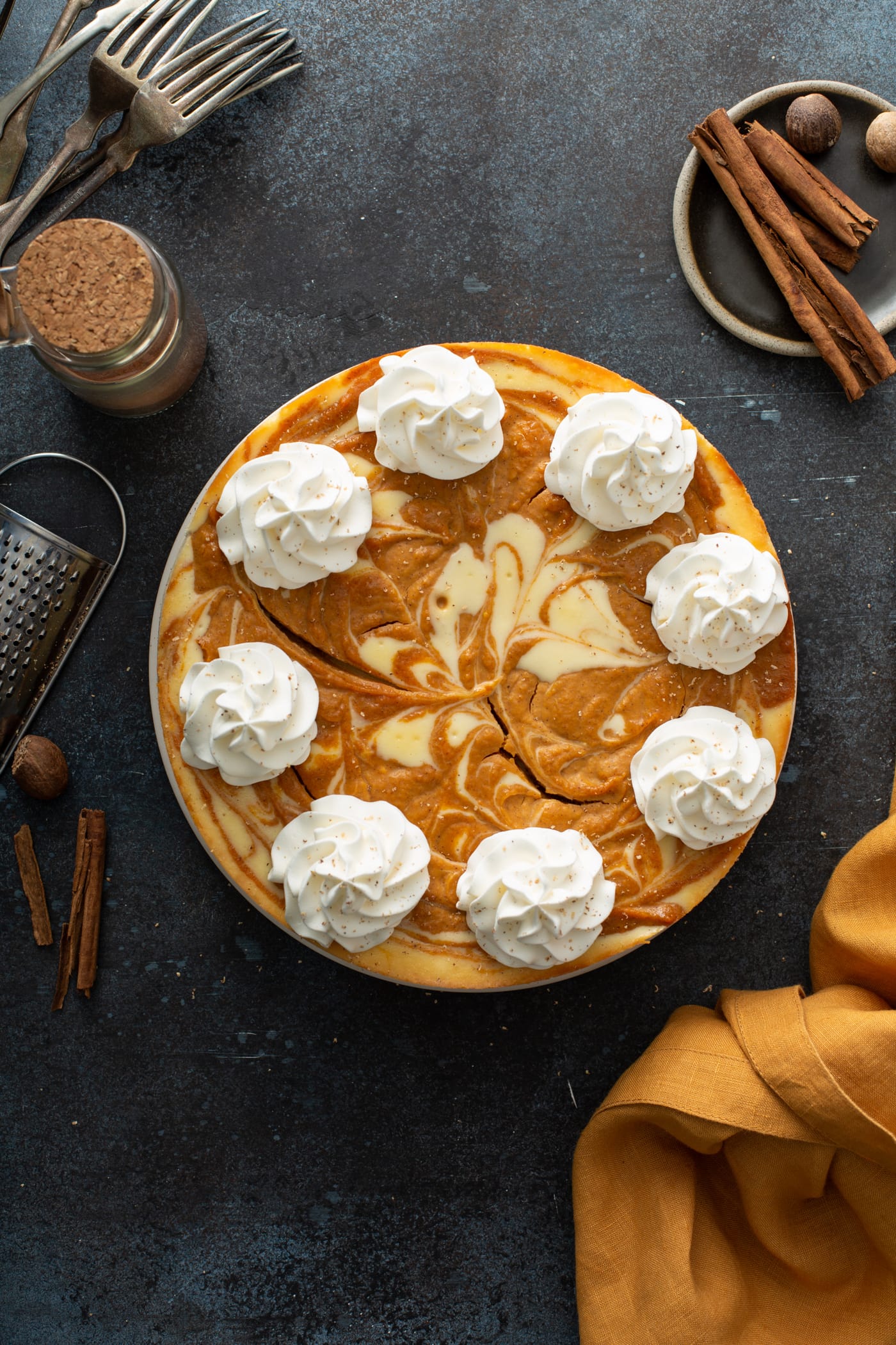 A swirled pumpkin cheesecake topped with dollops of whipped cream.