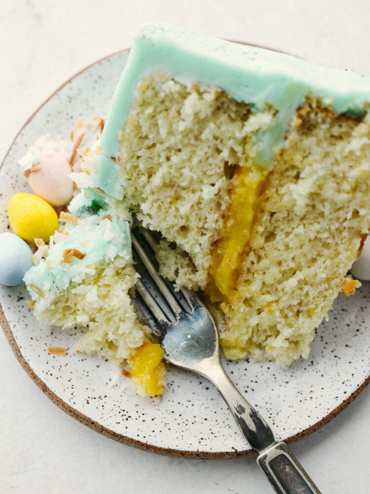 A slice of cake on a plate with a fork cutting into it. 