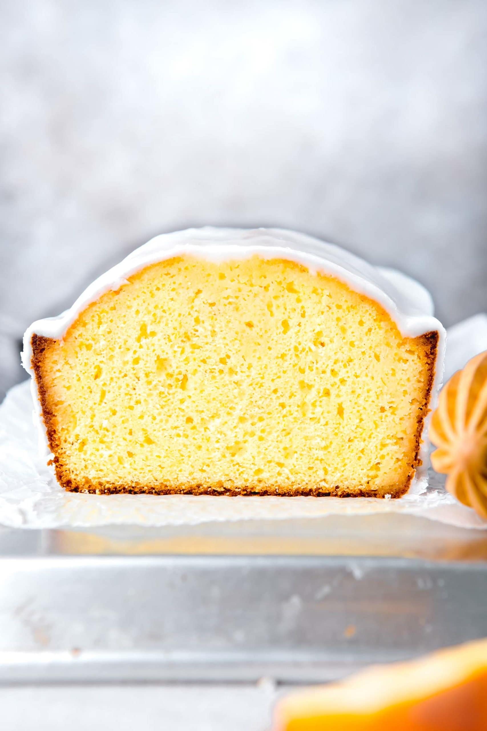 a photo of the cross section of an iced lemon loaf cake. 