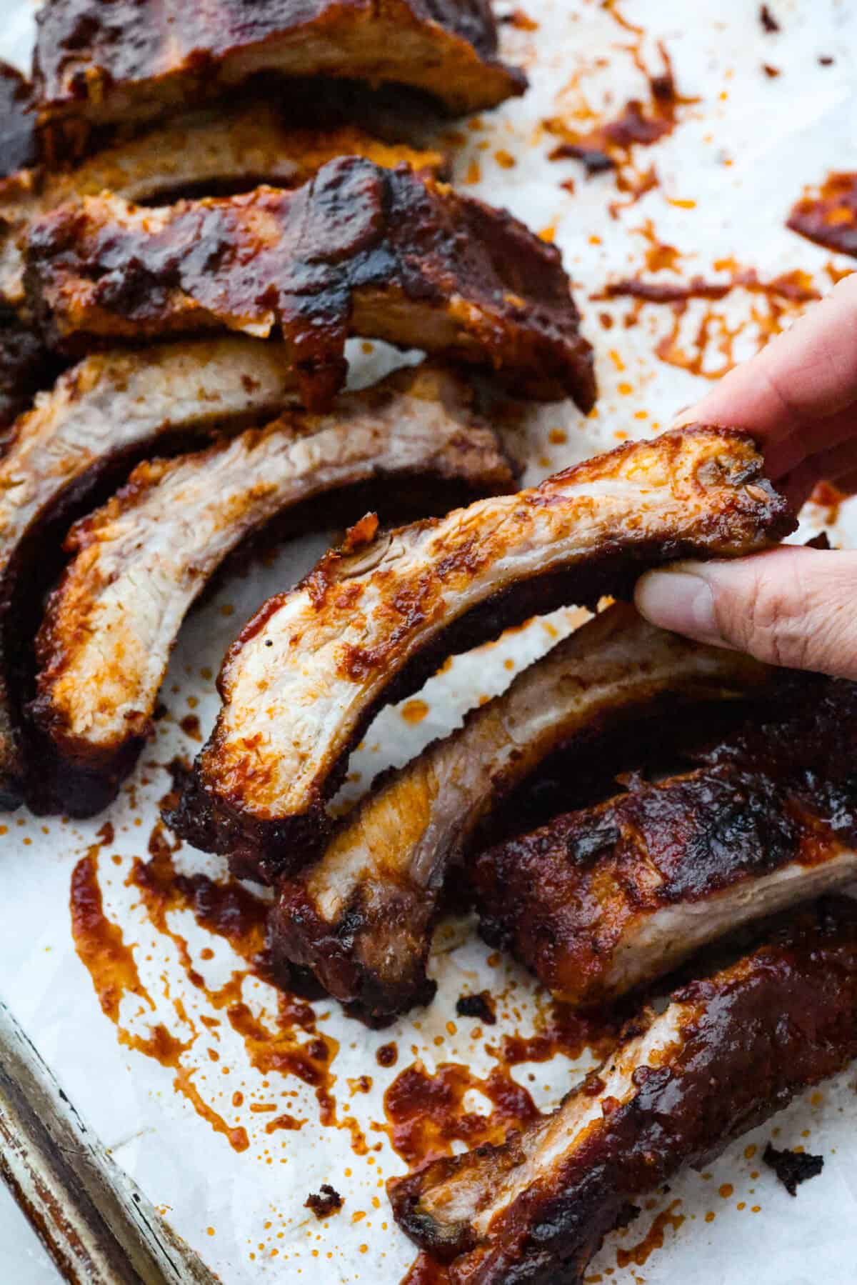 Someone picking up a grilled bbq rib/ 