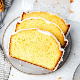 a photo of three slices of lemon loaf cake laying on a white plate.